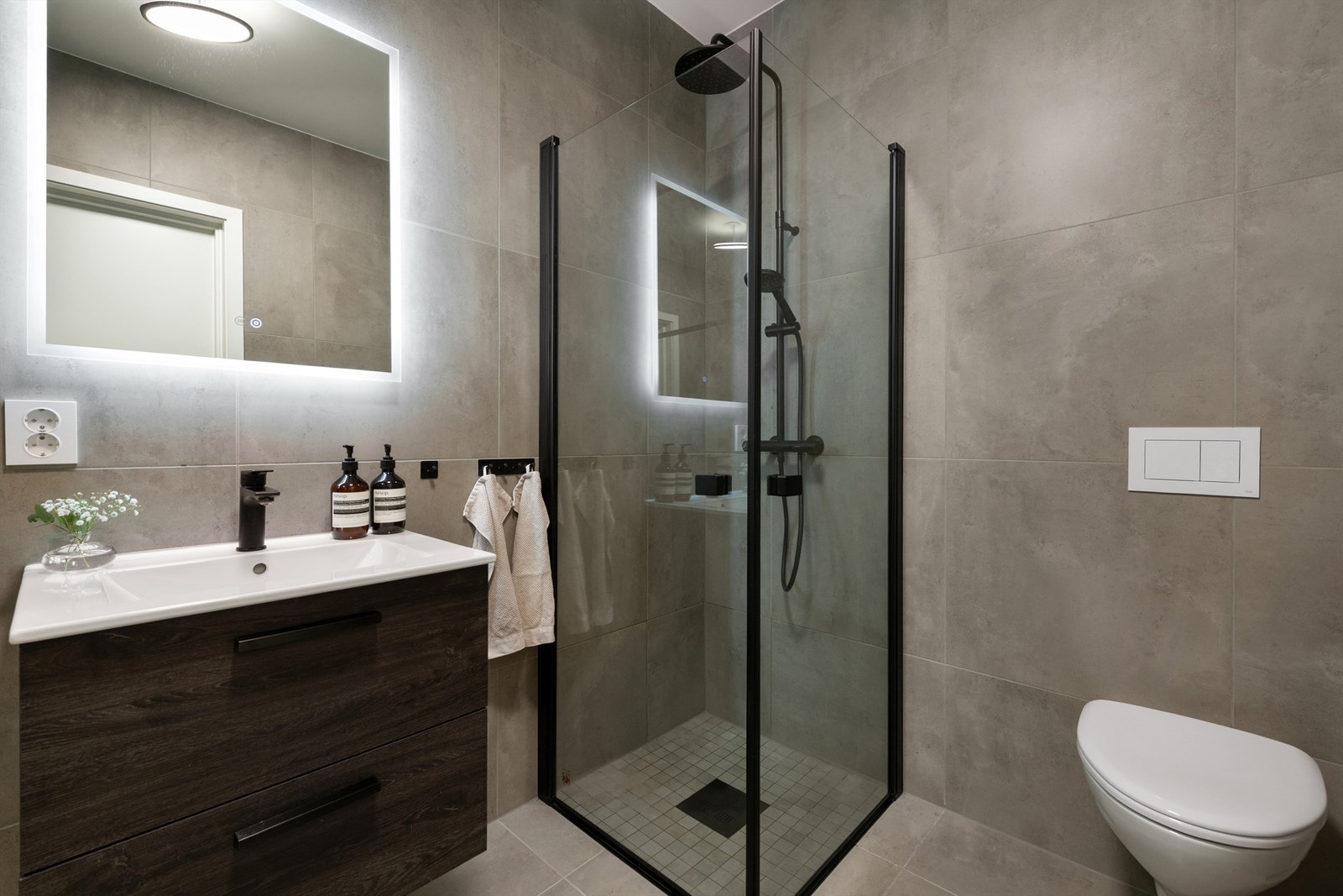 Badet er godt belyst og innredet med servant, vegghengt dusjamatur og toalett, samt elektrisk gulvvarme. Galleribilde