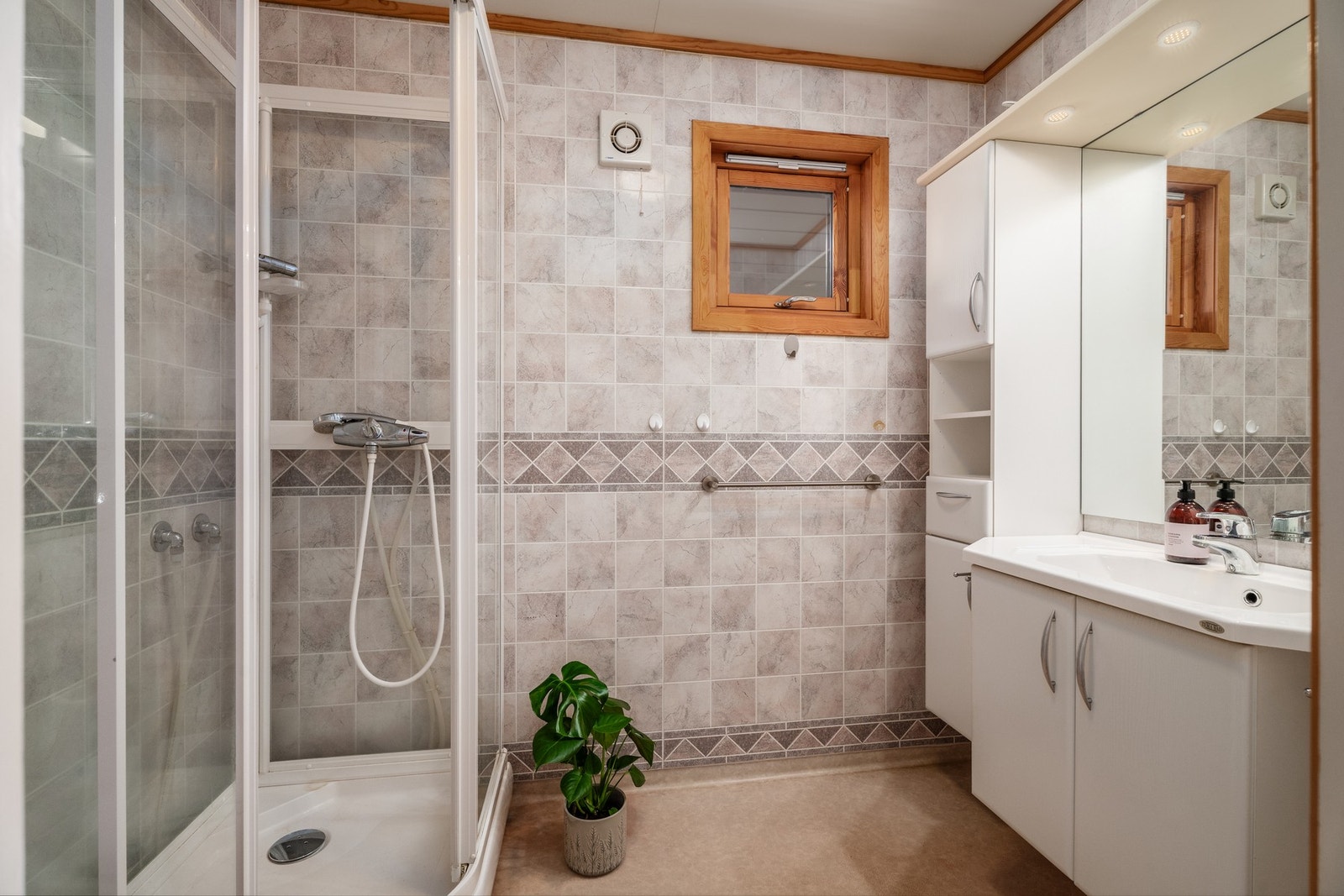Badet har dusjkabinett, legg også merke til vindu med klaffventil samt elektrisk styrt vifte. Galleribilde