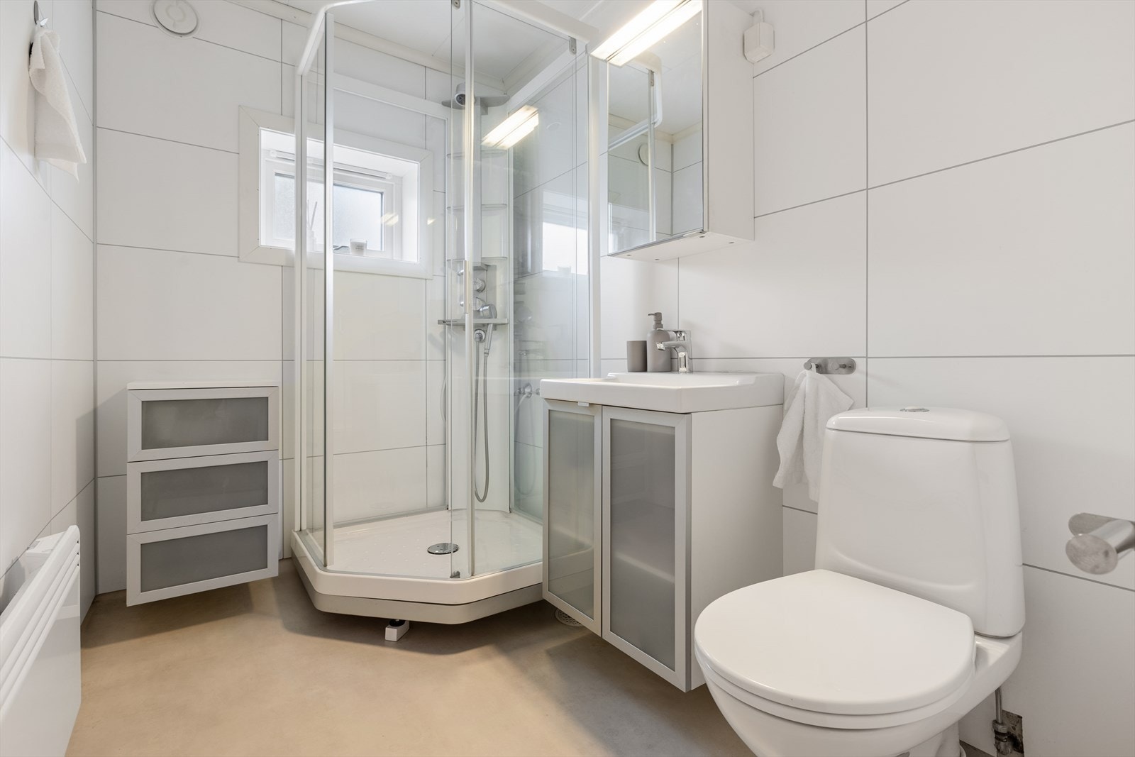 Lyst baderom innredet med nedfelt servant, toalett og dusjkabinett. Galleribilde
