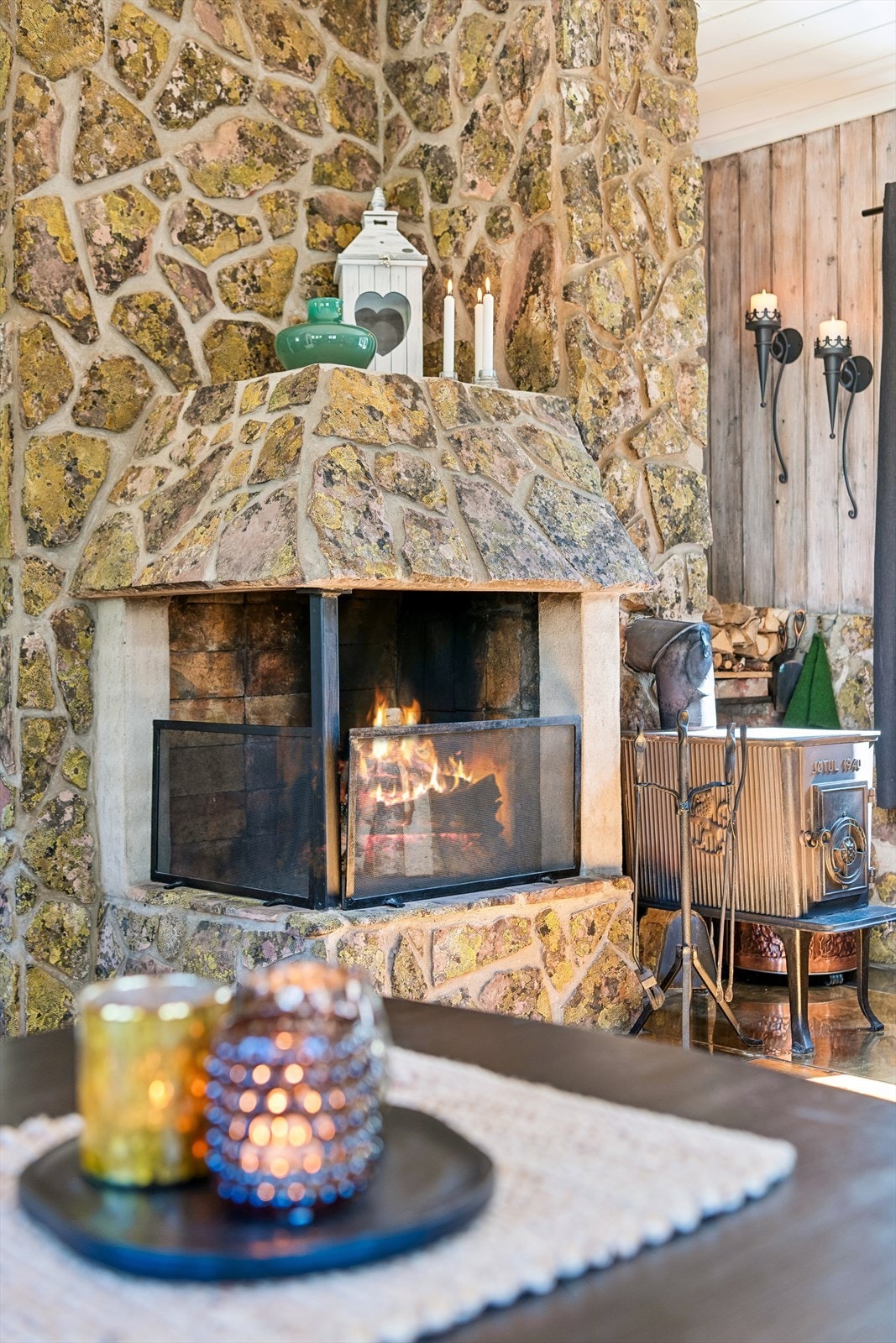Den massive peisen er forblendet med naturstein og har både åpen grue og tilkoblet vedovn for varme og hygge. Galleribilde