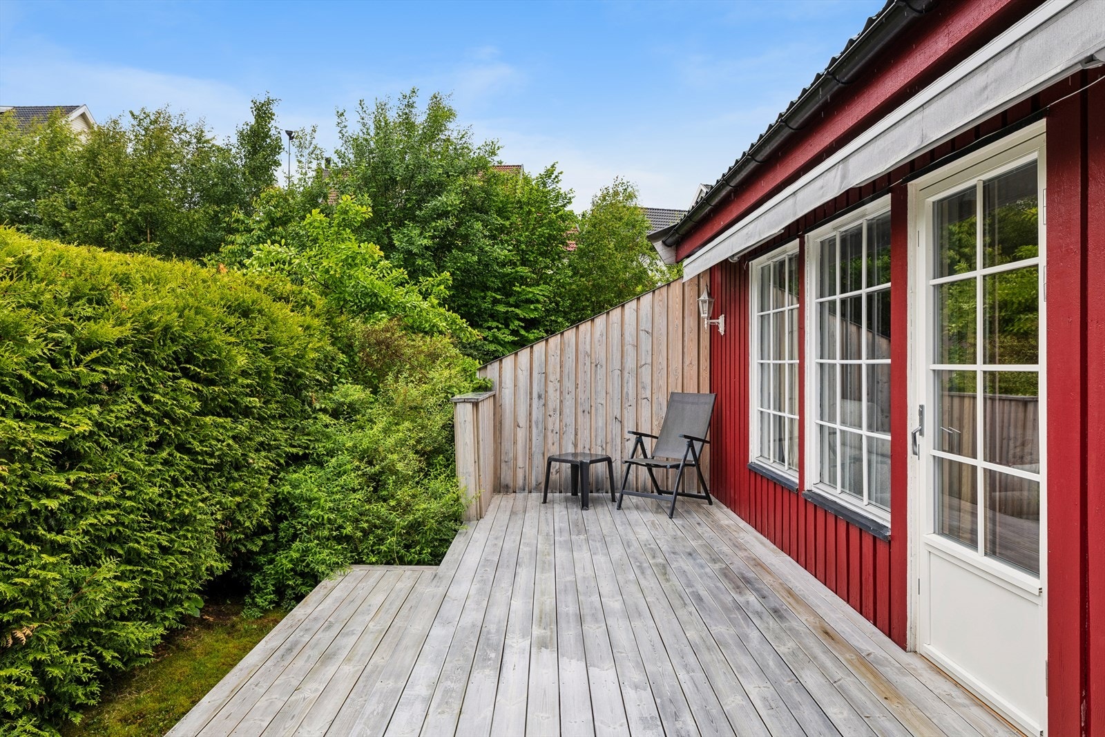 Den usjenerte terrassen er skjermet av hekk på sidene og gir plass til å møblere med både hagemøbler og grill. Galleribilde