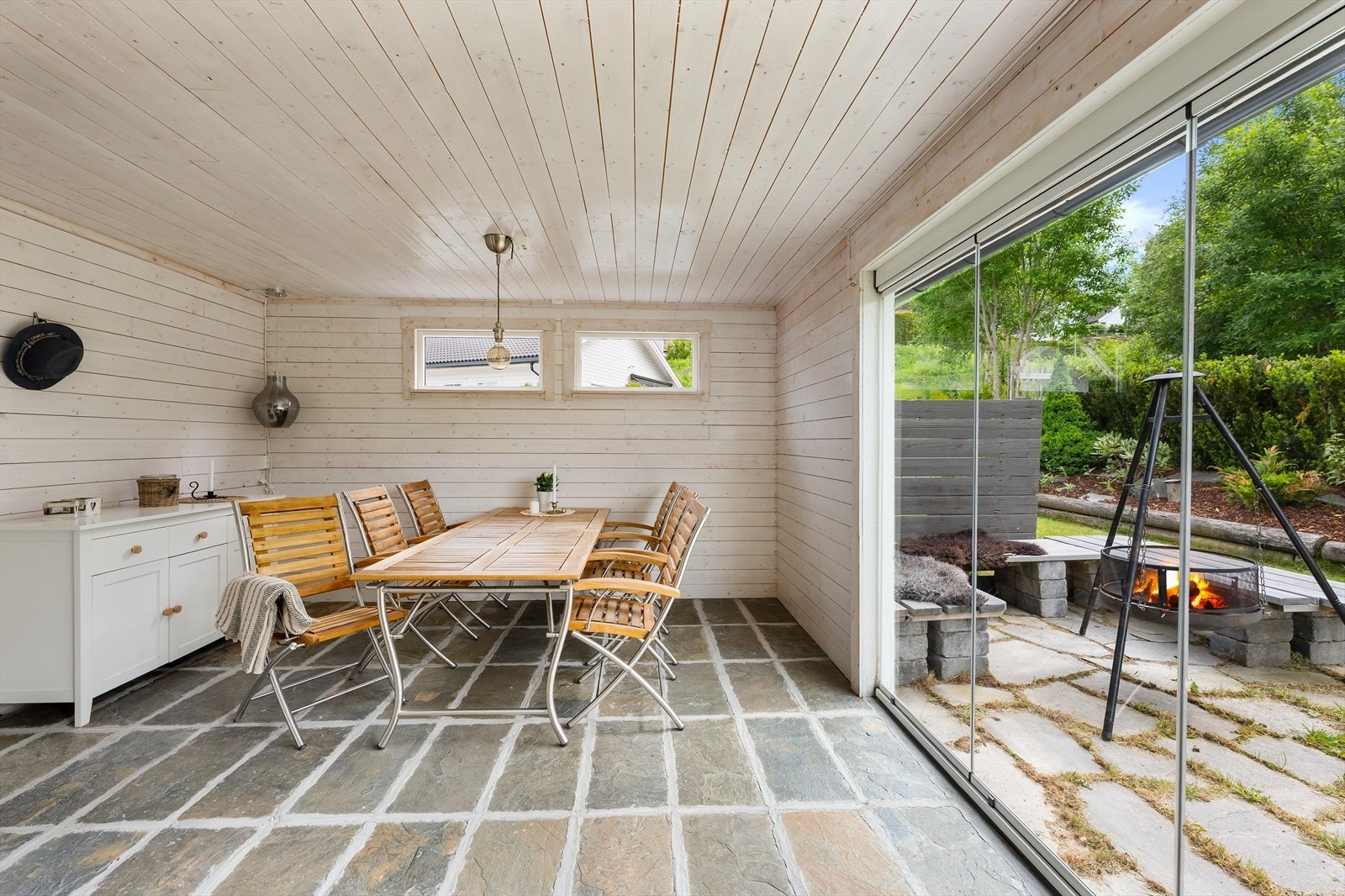 Fra hagestuen er det direkte utgang til en hellelagt uteplass med bålpanne. Galleribilde