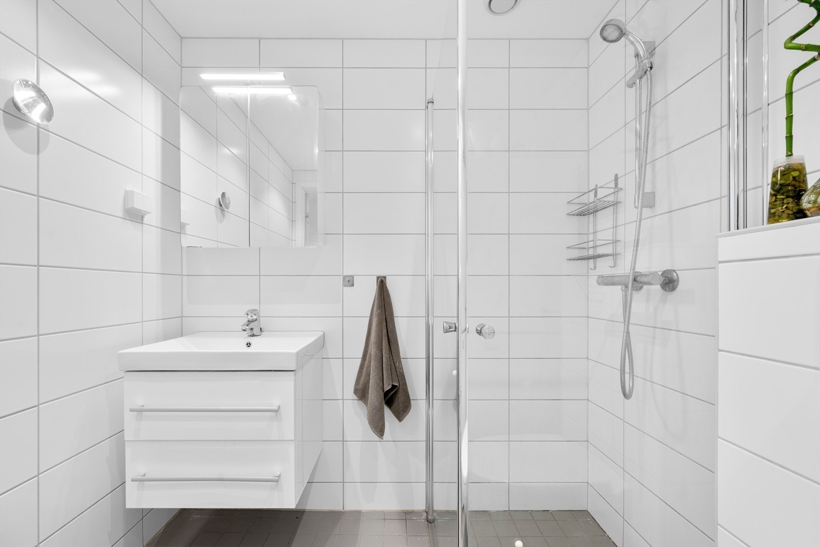 Badet er praktisk utformet med dusjhjørne i glass, servant med underskap og speilskap som gir god oppbevaringsplass. Samt er det opplegg for vaskemaskin. Galleribilde