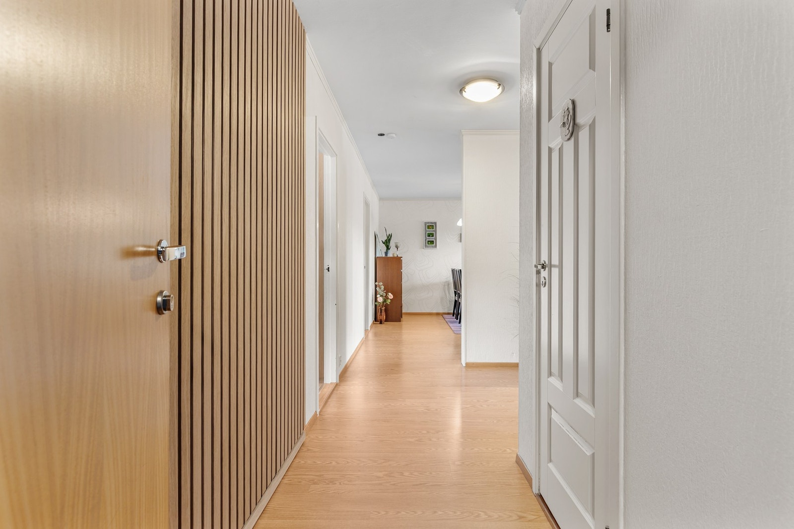 Romslig entré/gang med laminat på gulv og en moderne kontrastvegg med spiler Galleribilde