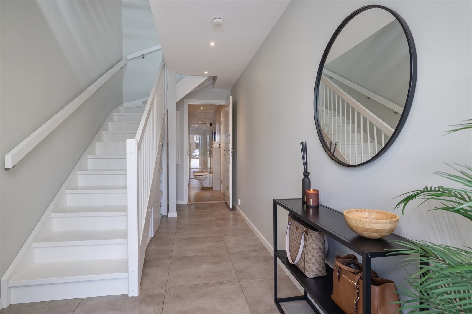 Entreen har flislagt gulv, lyse overflater, downlights i taket og hvitmalt tretrapp mellom etasjene. Galleribilde