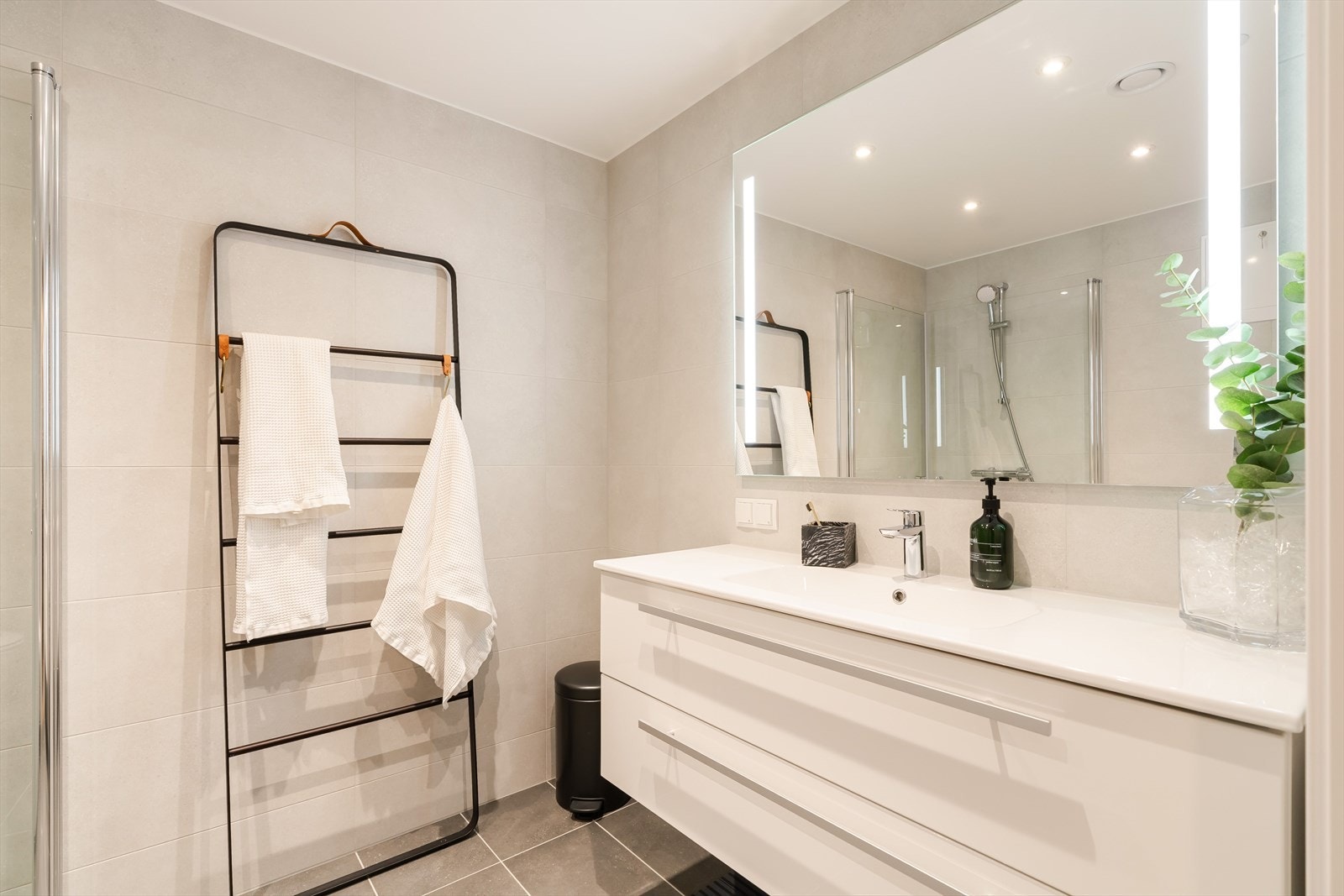 Her fra badet som ligger i tilknytning til hovedsoverommet. Veggene på badet er kledd med lyse fliser, og det er downlights i himlingen og grå fliser på gulvet. Galleribilde