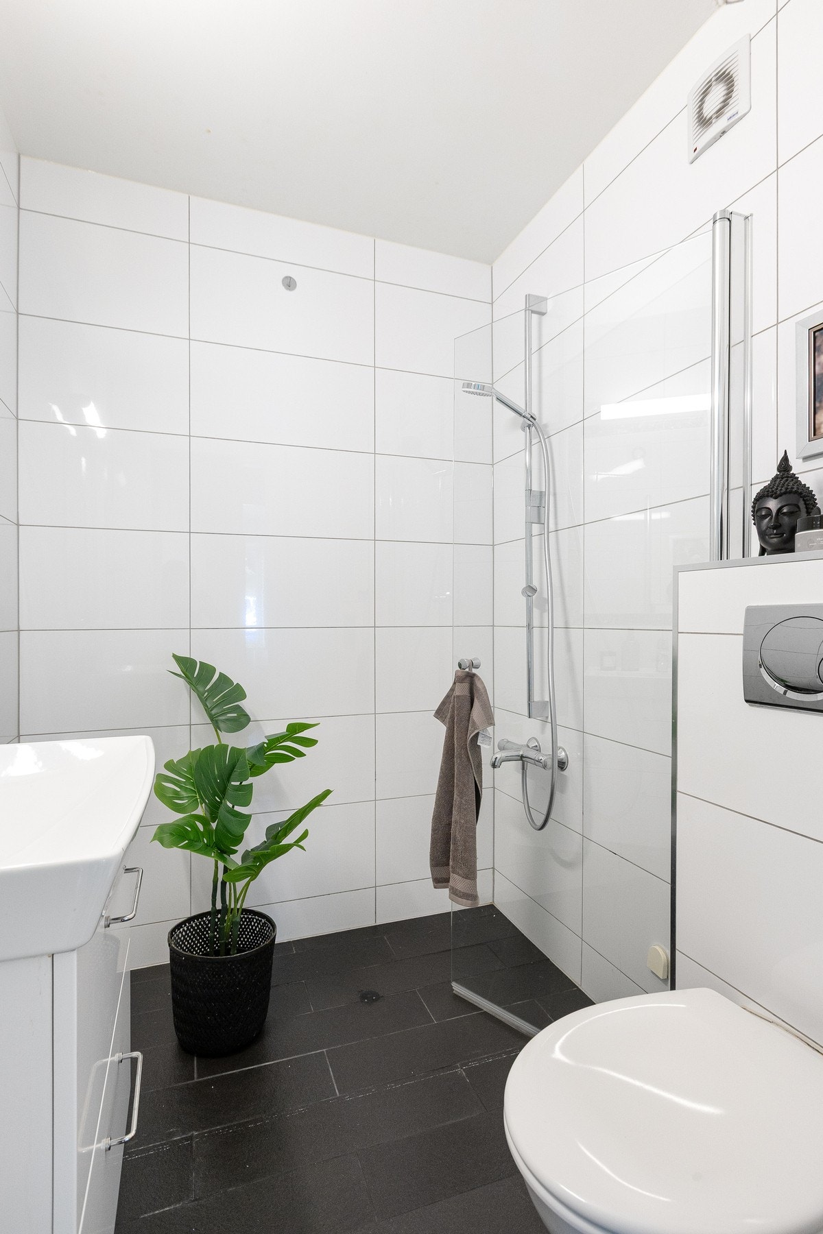 Videre er badet utstyrt med vegghengt toalett, servant med underskap, innfliset speil med overlys samt dusjnisje med inn- og utadslående dusjdører. Galleribilde