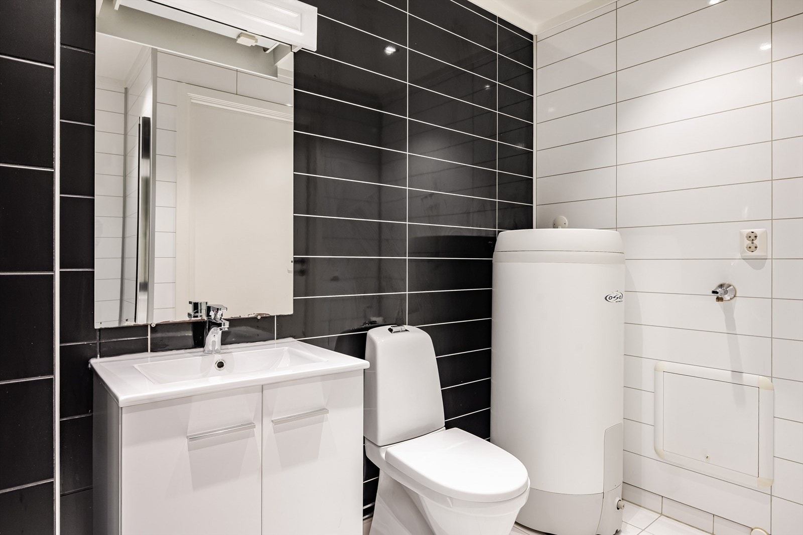 Badet er flislagt og det er elektriske varmekabler i gulvet. Baderomsinnredning med servantskap med heldekkende servant og speil med lys og elektrisk uttak i overkant. Galleribilde