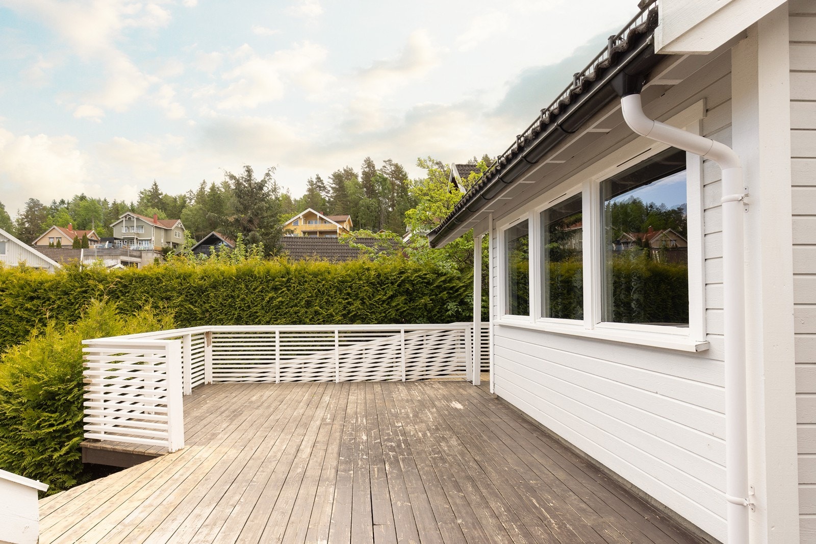 Stor terrasse som strekker seg rundt deler av huset og gir flere soner for utemøbler. Galleribilde