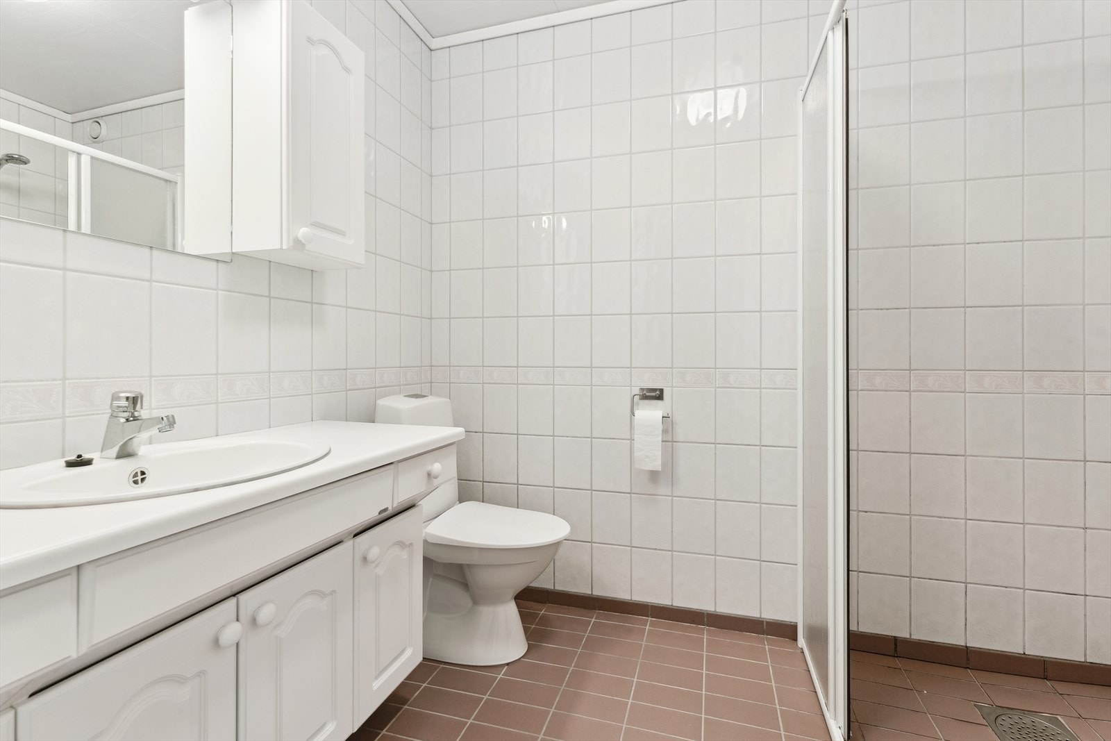 Bad i utleigedelen med dusj, toalett og opplegg for vaskemaskin. Golvet har flis med varmekablar. Galleribilde