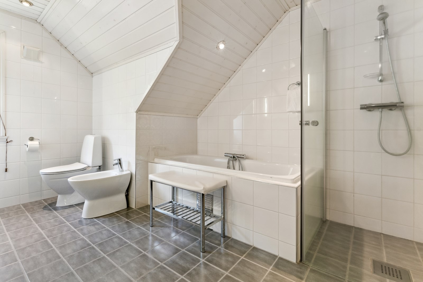 Badet er utstyrt med både innflisa badekar og dusj med hengsla glasdører. Golvet har flis med varmekablar. Galleribilde