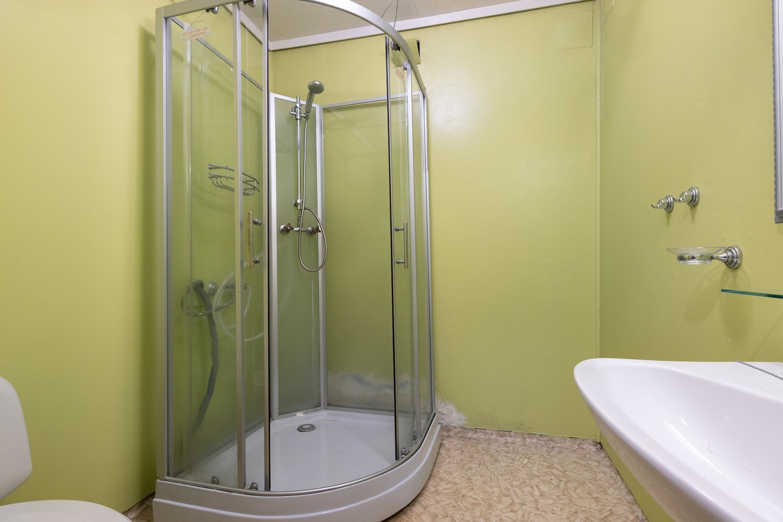 Badet har dusjkabinett og servant. Veggene er malt i en lys grønn farge. Galleribilde