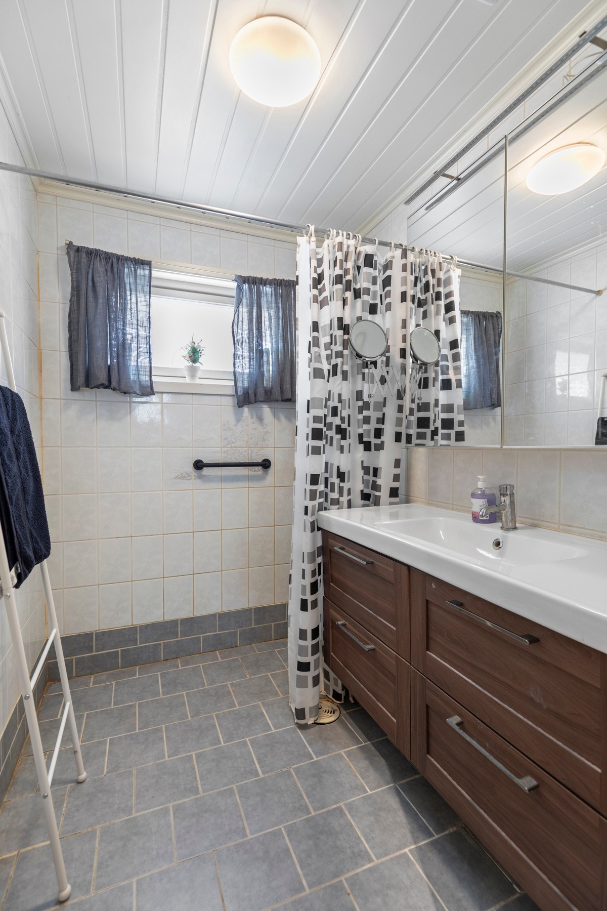 Badet har flislagt gulvoverflate med gulvvarme, og fliskledde vegger. Montert baderomsinnredning og dusj-på-vegg Galleribilde