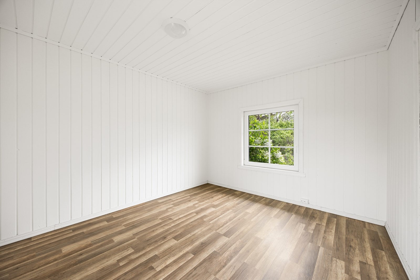 Det andre soverommet i etasjen har laminatgulv og malte panelvegger. Galleribilde