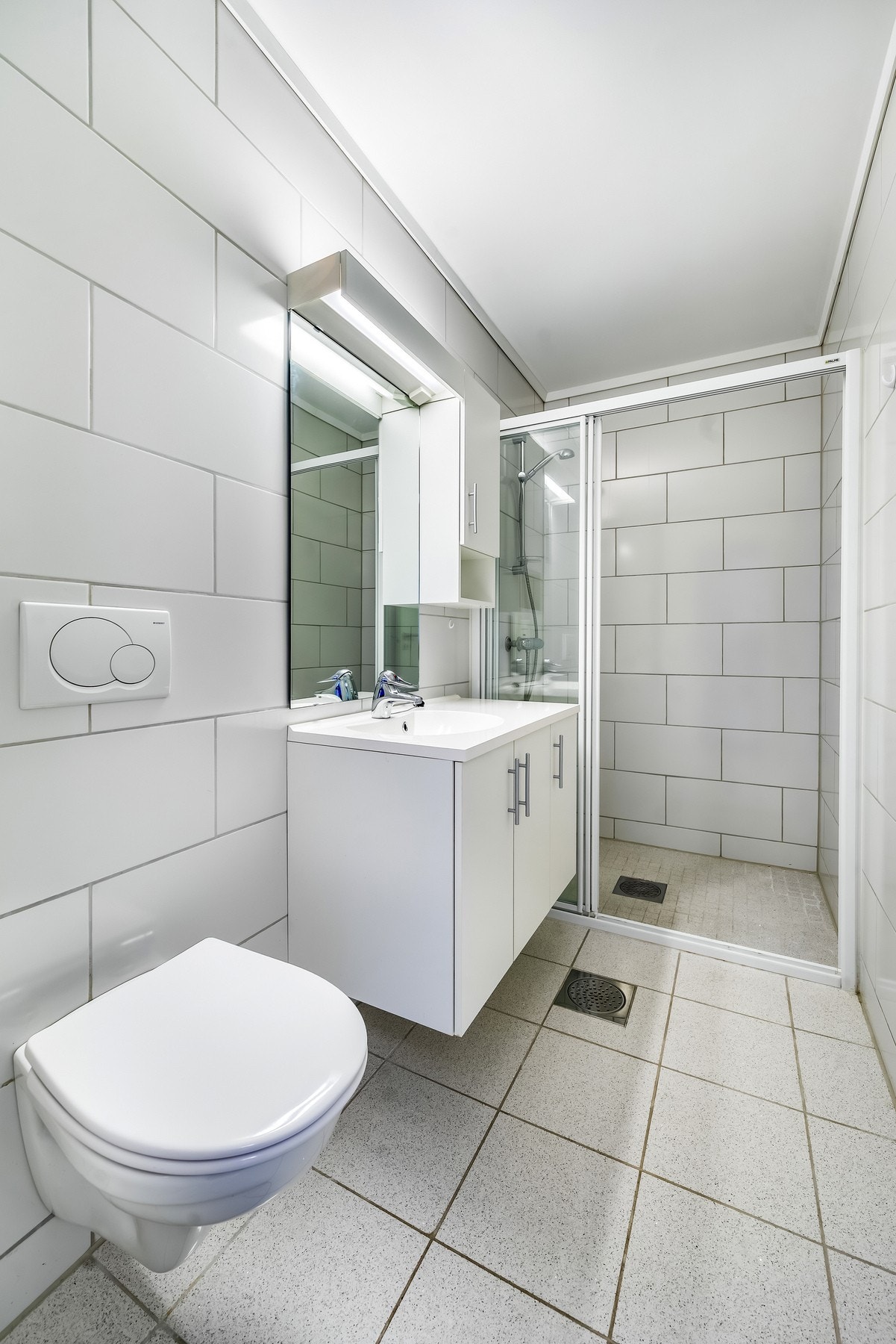 Bad 1. Lyst og stilrent bad med flislagte overflater som gir et rent og moderne uttrykk. Praktisk innredning og dusjløsning gir god komfort i hverdagen. Galleribilde