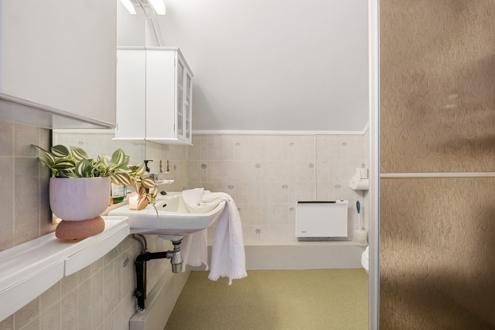 Badet på loftet har vegger med våtromstapet/belegg og malt tak. Gulvet har vinylbelegg. Galleribilde