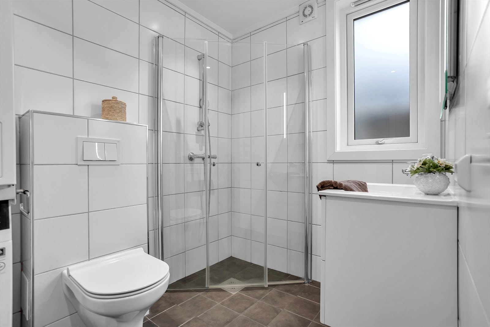 Badet fra 2022 har flislagte gulv og vegger, vegghengt toalett og dusjhjørne i herdet glass. Galleribilde