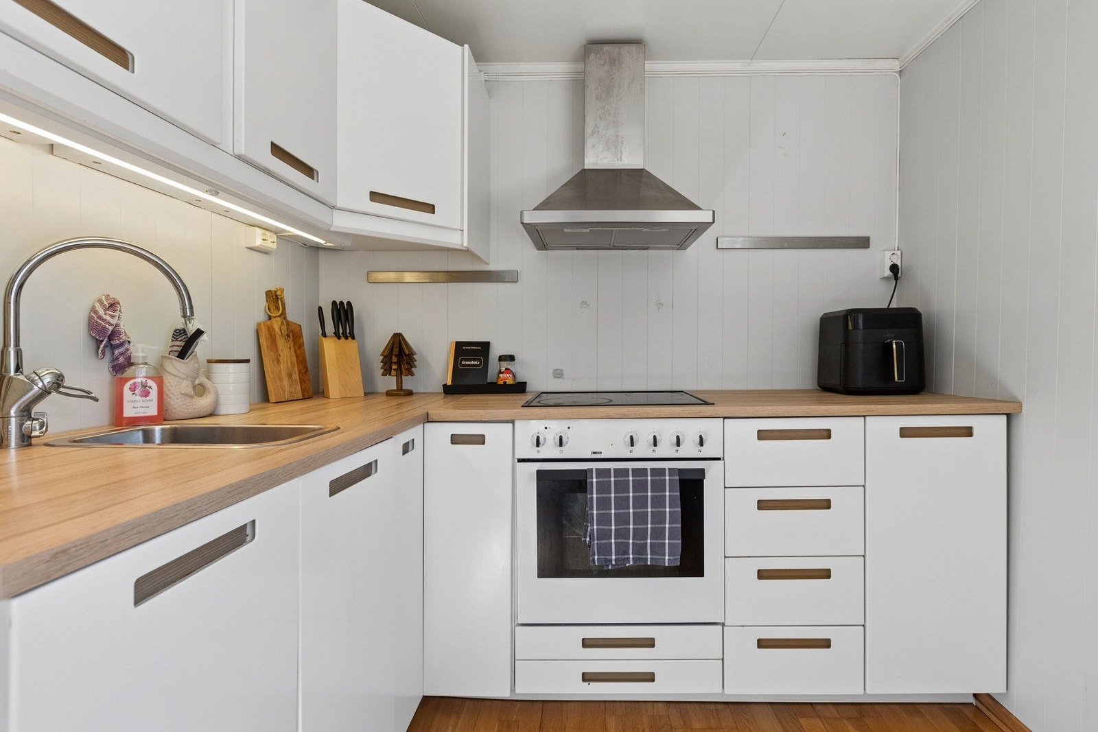 Kjøkkenet er praktisk innredet med moderne, hvite fronter og laminatbenkeplate. Galleribilde