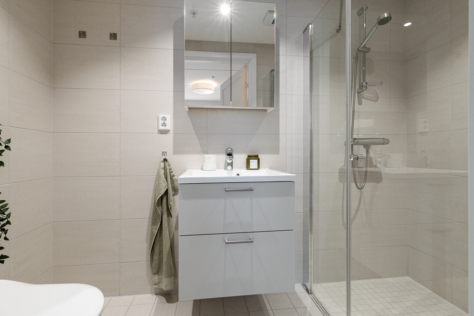Badet har moderne farge- og materialvalg med flislagte overflater, gulvvarme og downlights i himling. Galleribilde