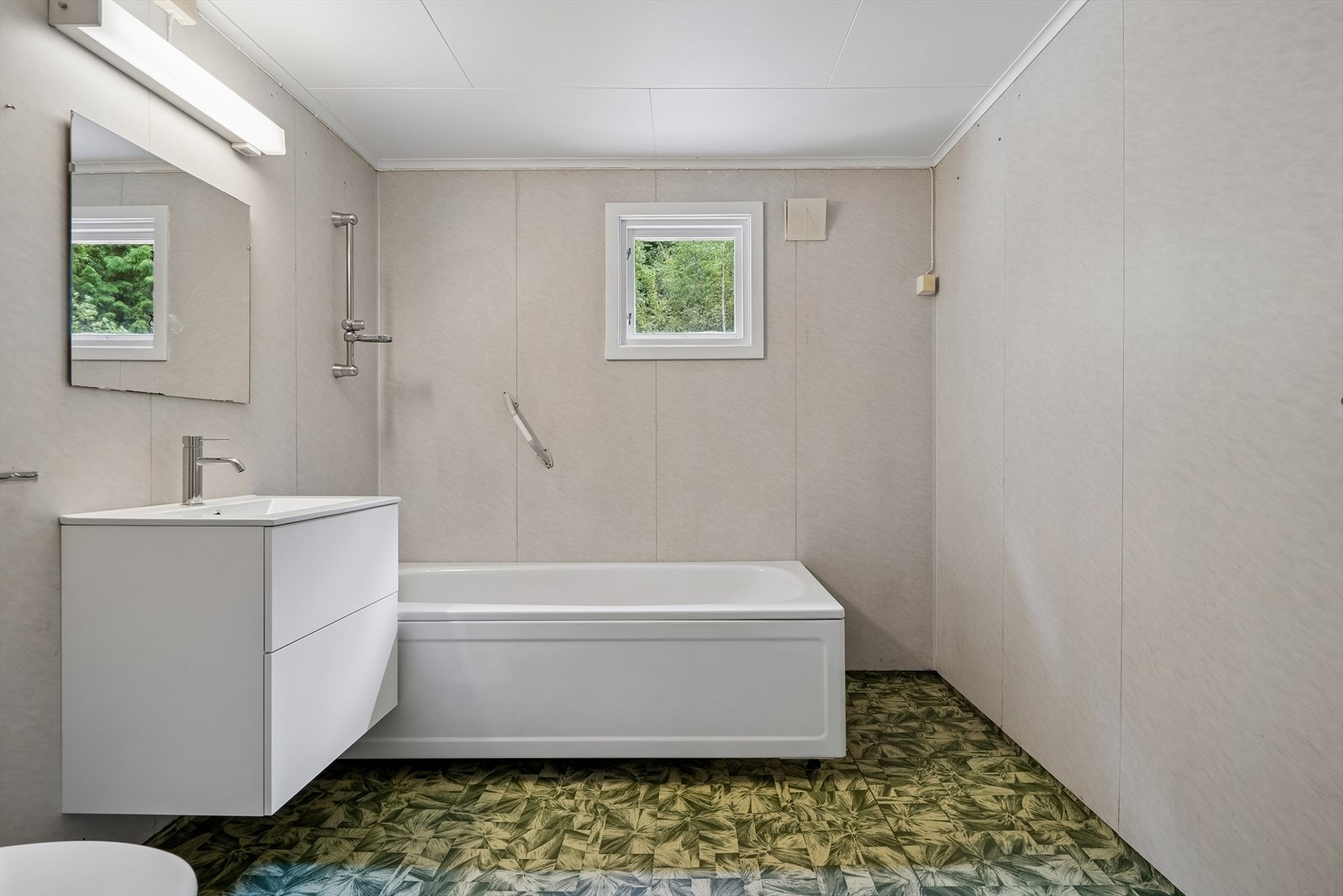 Badet er utstyrt med badekar, toalett og en nyere servantinnredning. Veggene har baderomsplater og gulvet har vinylbelegg. Galleribilde