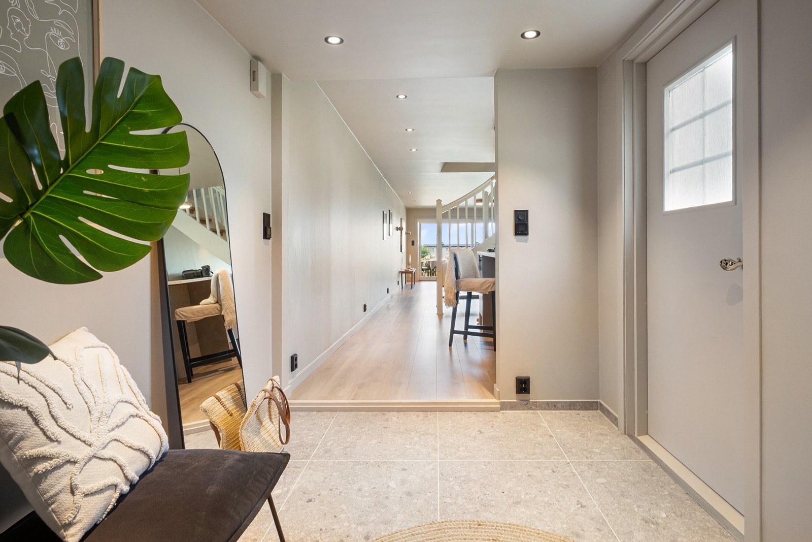 Entreen tar imot med flislagt gulv, downlights og en siktlinje som leder blikket mot stuen og uteområdet. Galleribilde