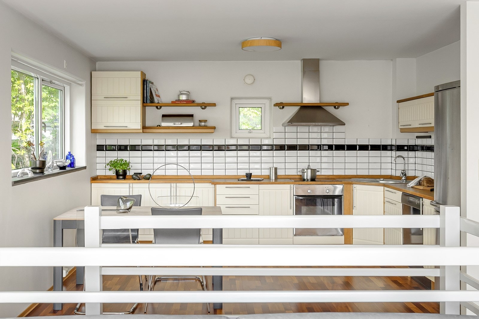 Kjøkkenet fyller halvannen vegg i åpen løsning mot stuen. Fronter og skuffer er sandfargede, innrammet av benkeplate, sokler og sidevegger i heltre med brun tone. Galleribilde