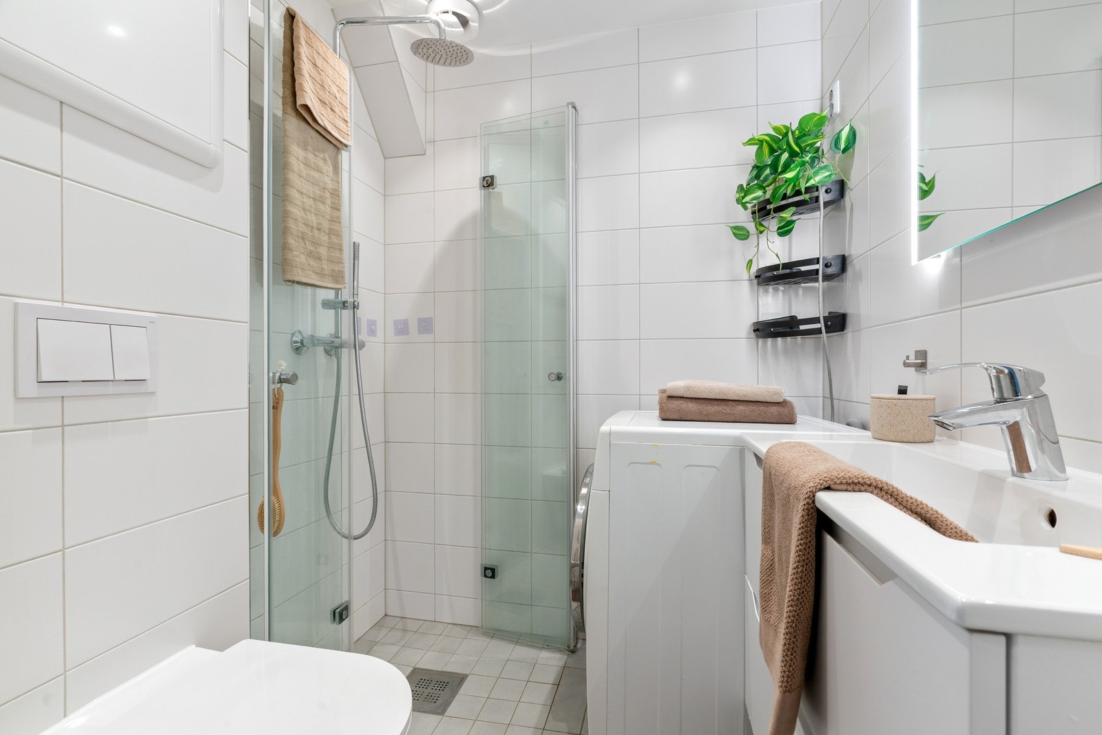 Badet har en tidløs stil med moderne innredning, vegghengt toalett og dusjsone med innfellbare glassvegger. Det er tilrettelagt for tilkobling av vaskemaskin på badet. Galleribilde