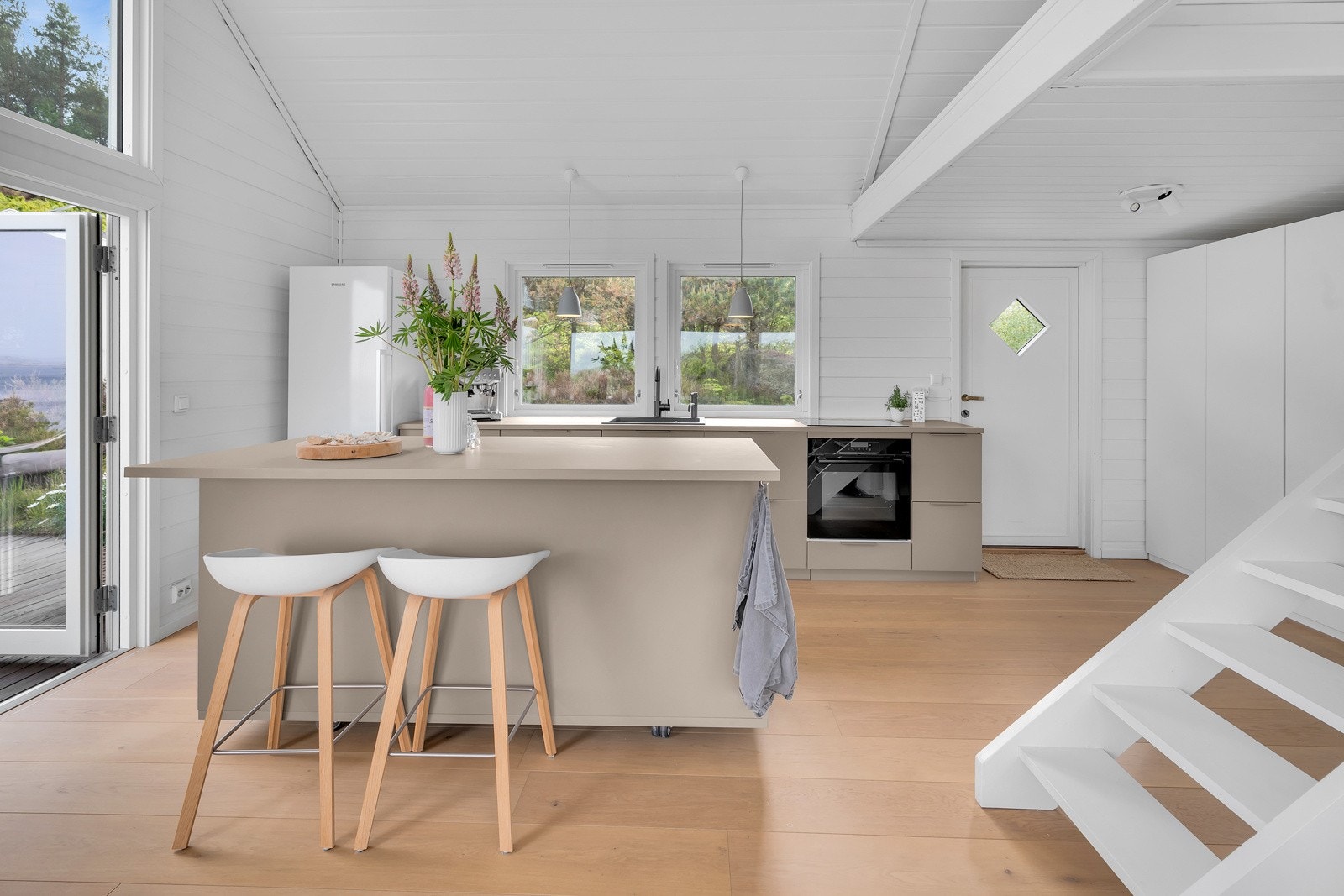 Kjøkkenet er moderne og flott i en dus, delikat farge og har kjøkkenøy med sitteplasser. Galleribilde