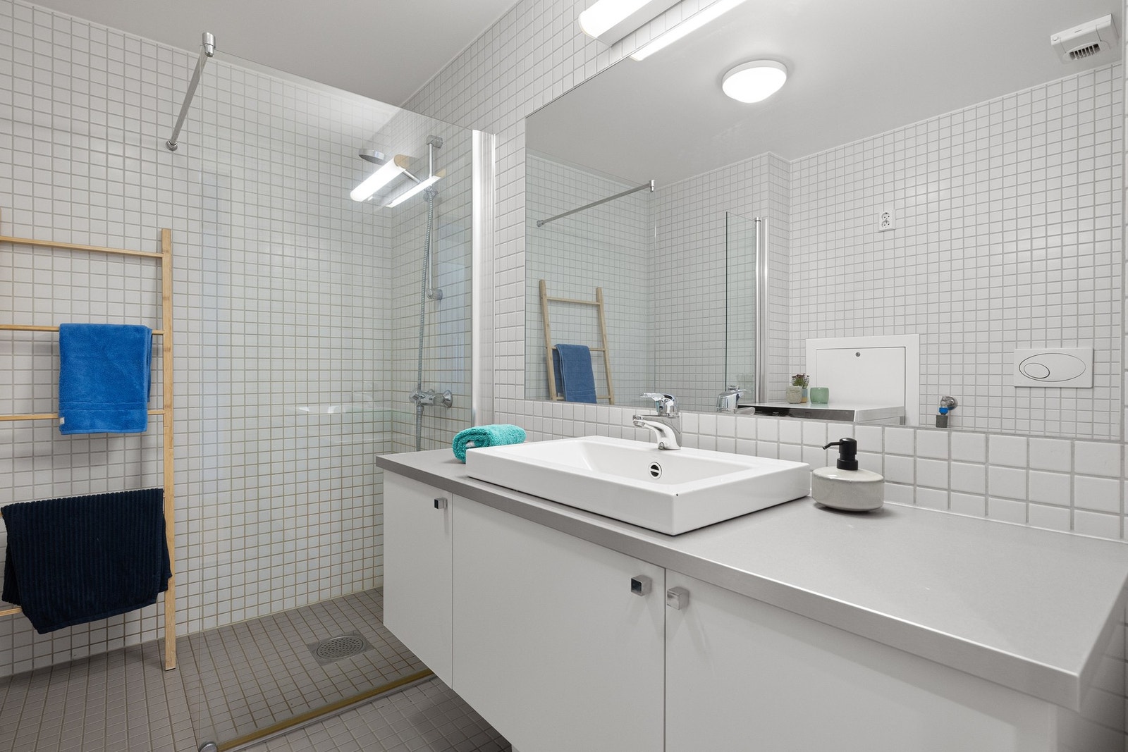 Badet er innredet med servantseksjon med skap, dusjhjørne med skillevegg i glass og vegghengt toalett. Galleribilde