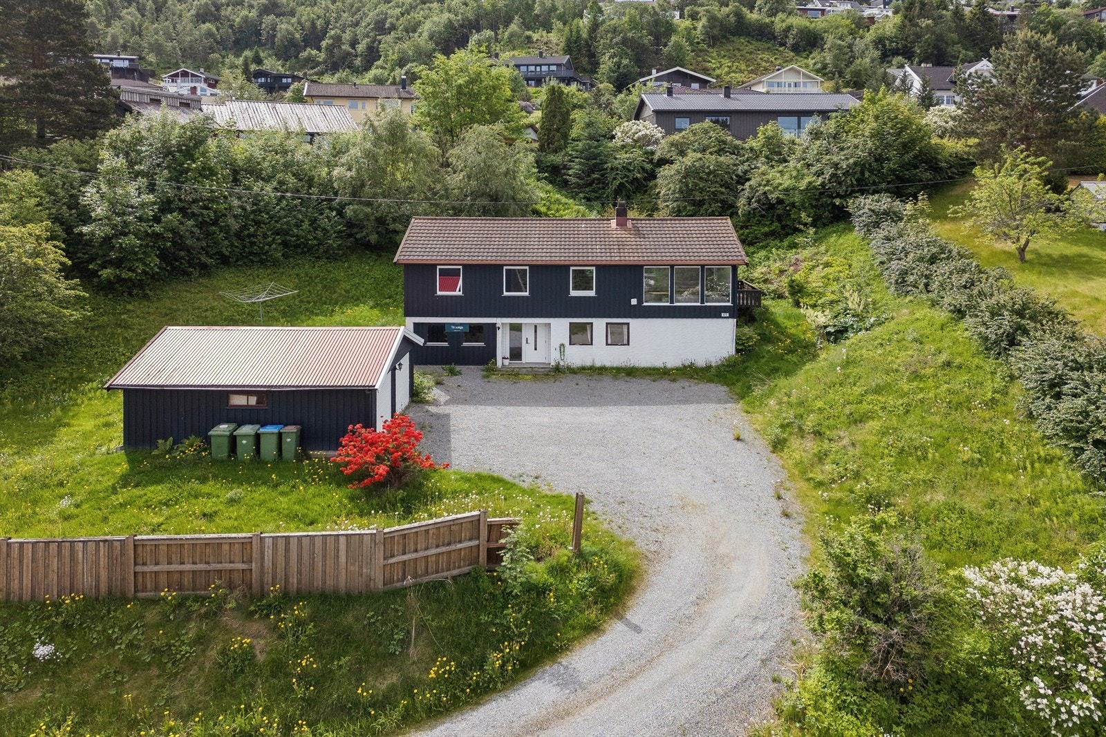 Eiendommen ligger i et relativt skrånende terreng med plen og beplantning. Stor, gruset gårdsplass med gode parkeringsmuligheter. Galleribilde