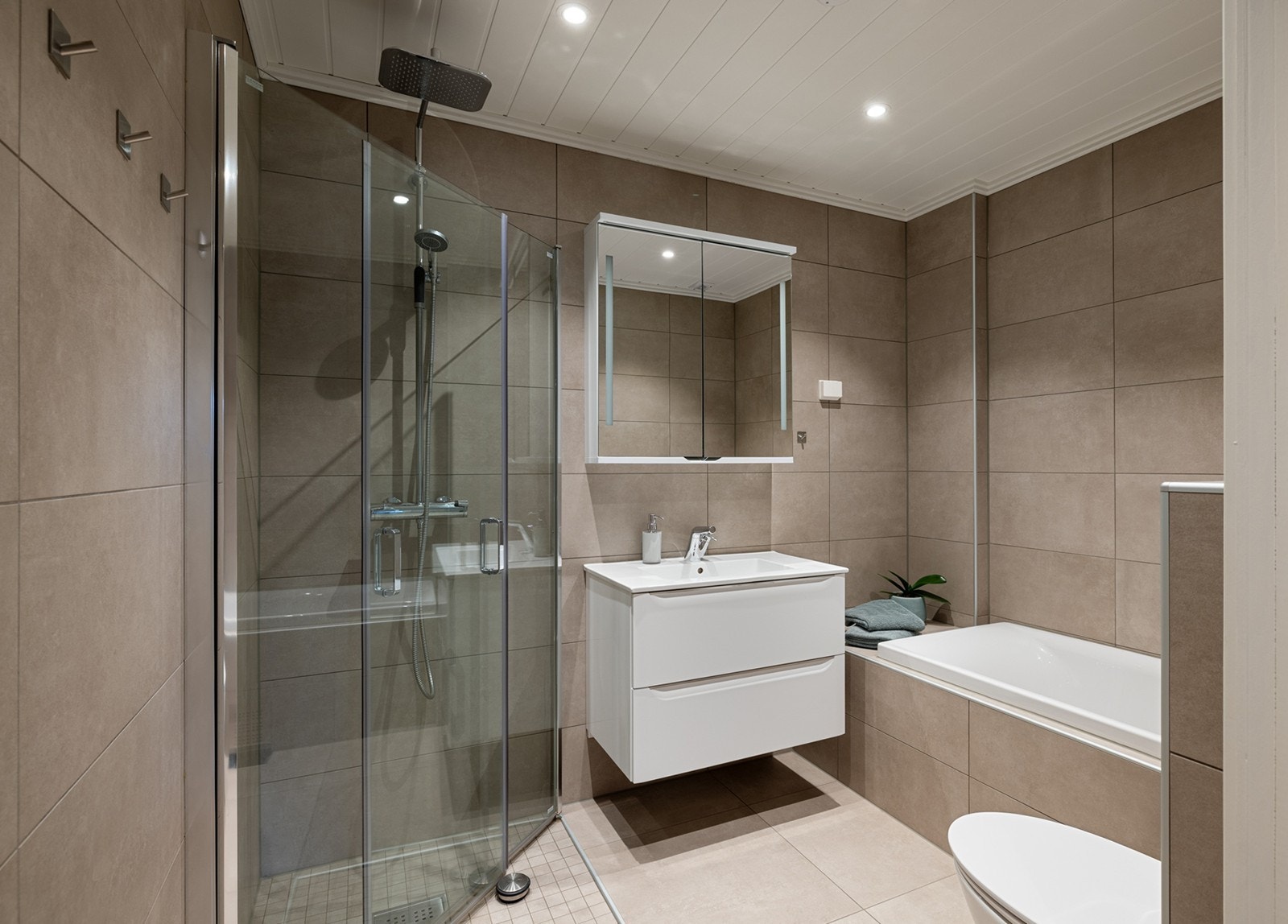 Pent, helfliset bad med gulvvarme og downlights. Badet er innredet med moderne baderomsinnredning, speilskap med stikkontakt, vegghengt toalett. Galleribilde