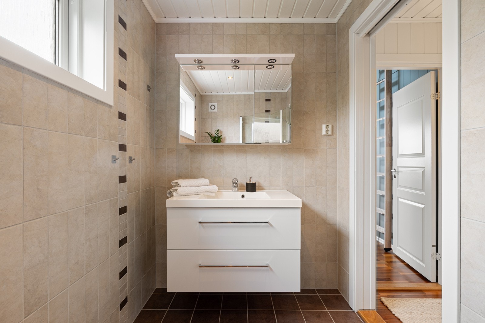 Lyst og innbydende bad med flislagt gulv og flislagte vegger i tidløse fargetoner. Gulvvarme gir god komfort året rundt. Badet er innredet med servant i moderne baderomsinnredning med underskap, speilskap med integrert belysning og stikkontakt. Galleribilde