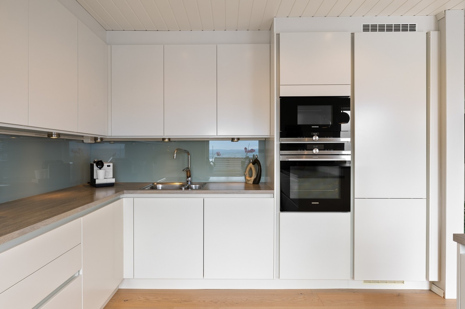 Kjøkkenet er innredet med laminert benkeplate og glassplate mellom benk og overskap, som gir et elegant uttrykk og er praktisk i daglig bruk. Galleribilde
