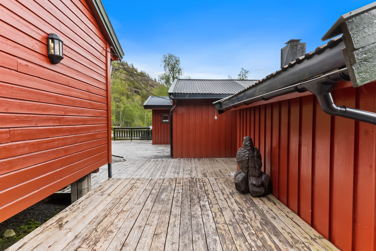 Terrassen går mellom hytte, anneks og frittstående bod. Galleribilde