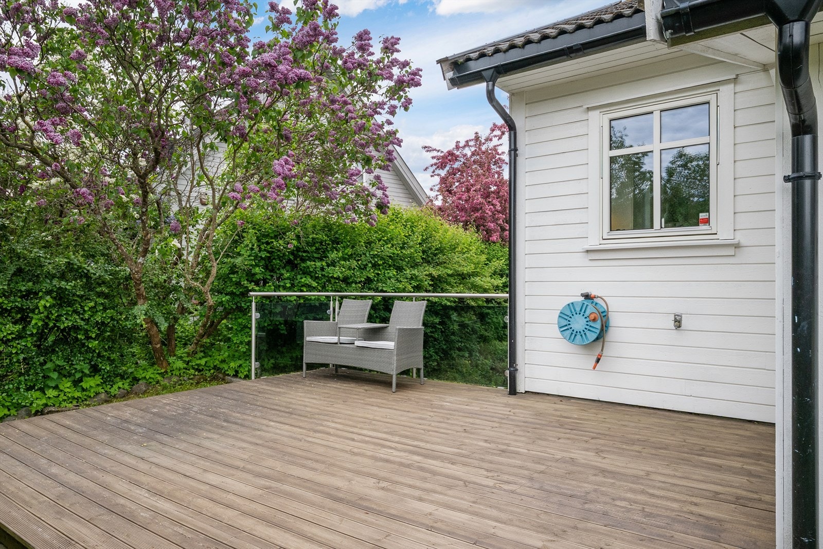 Fin, skjermet uteplass med platting og glassrekkverk. Galleribilde