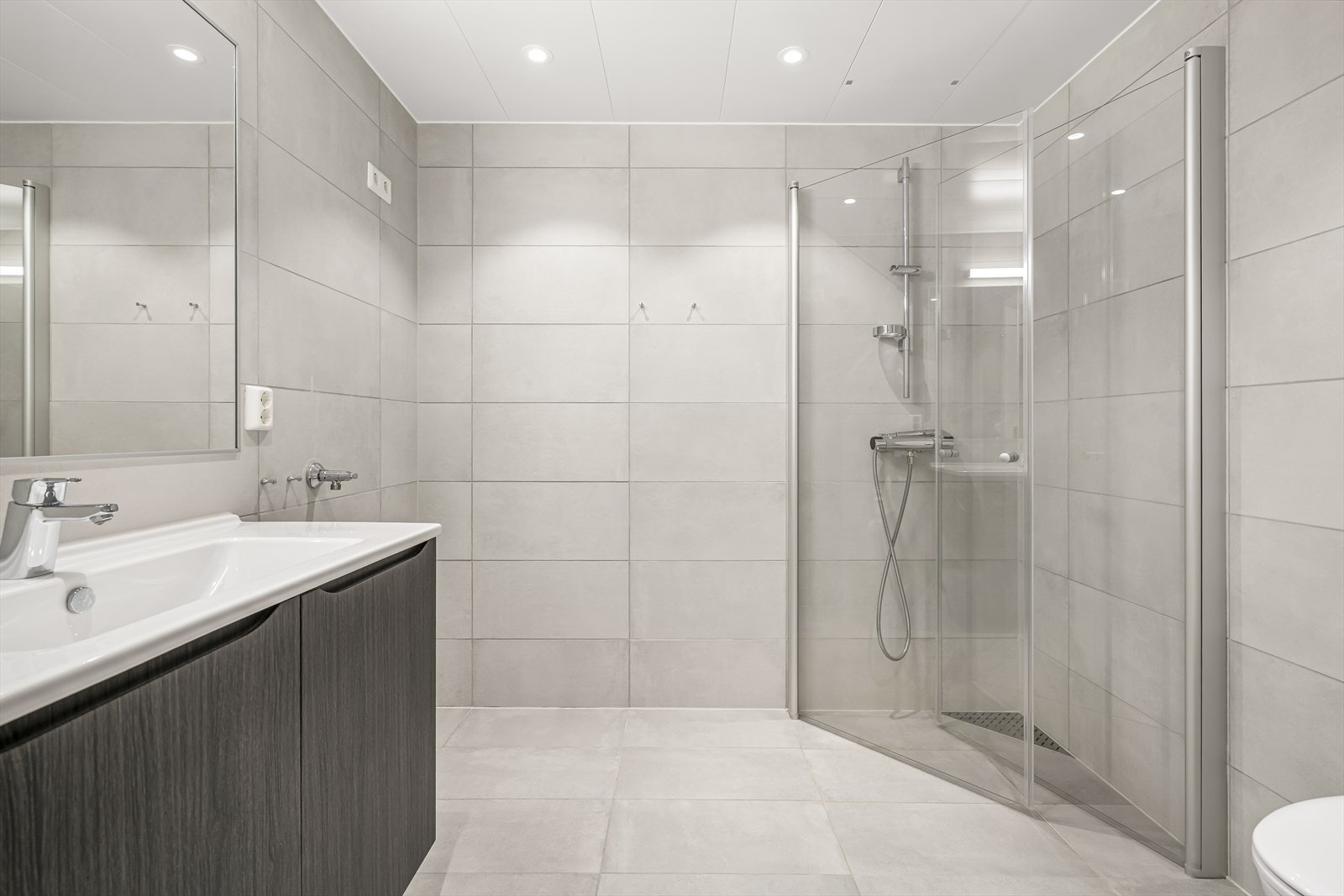 Badet er utført med store fliser på gulv og vegger. Galleribilde
