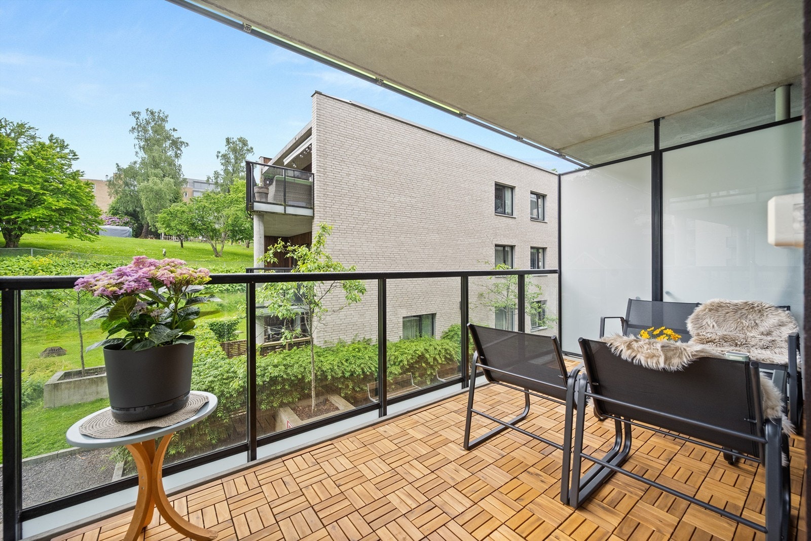 Balkongen er utført i betong med tremmer av tre på gulvet, og har et rekkverk i glass og metall. Galleribilde