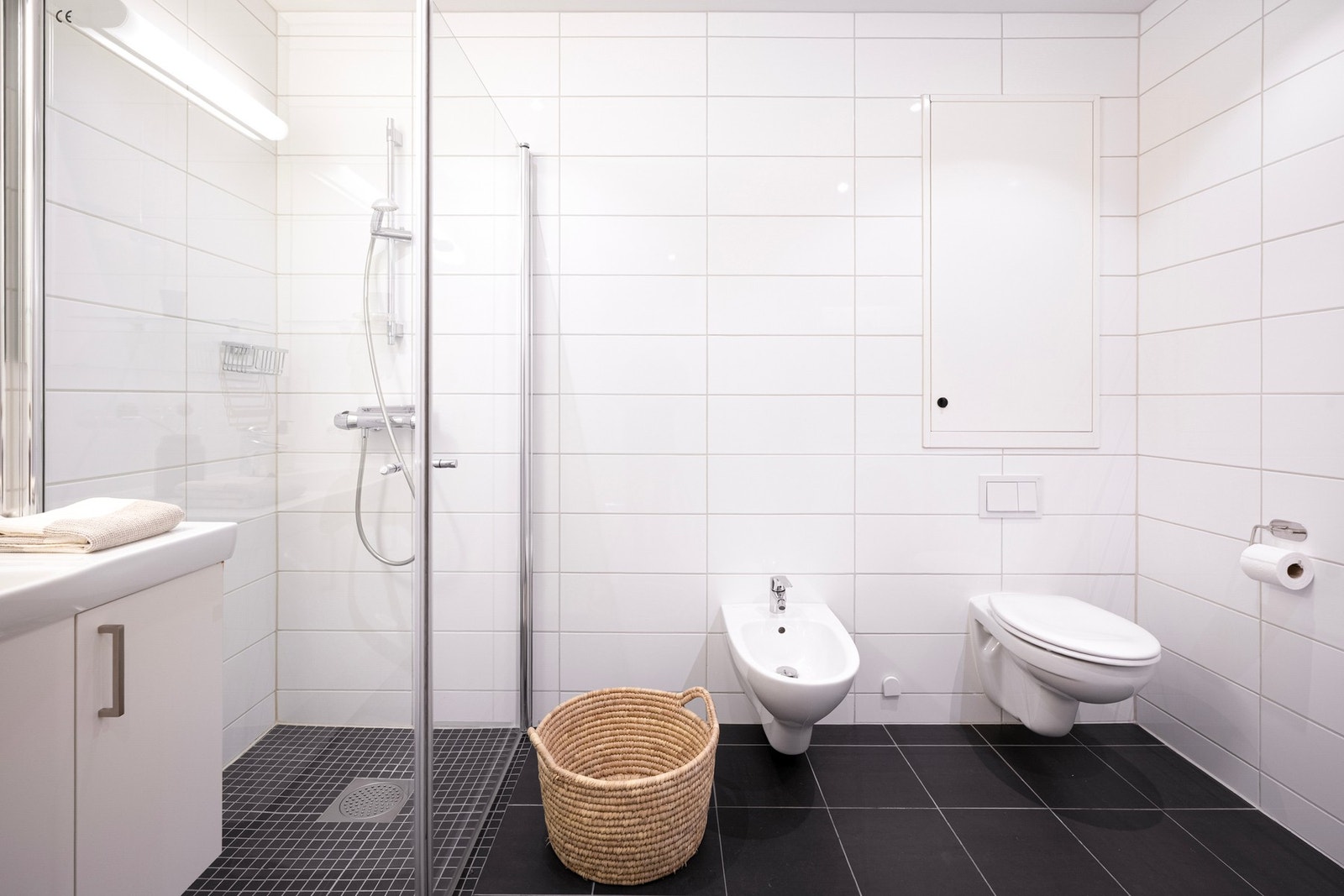 Badet er flislagt med hvite veggfliser og mørke gulvfliser, et tidløst og rent uttrykk som passer godt til resten av boligen. Galleribilde