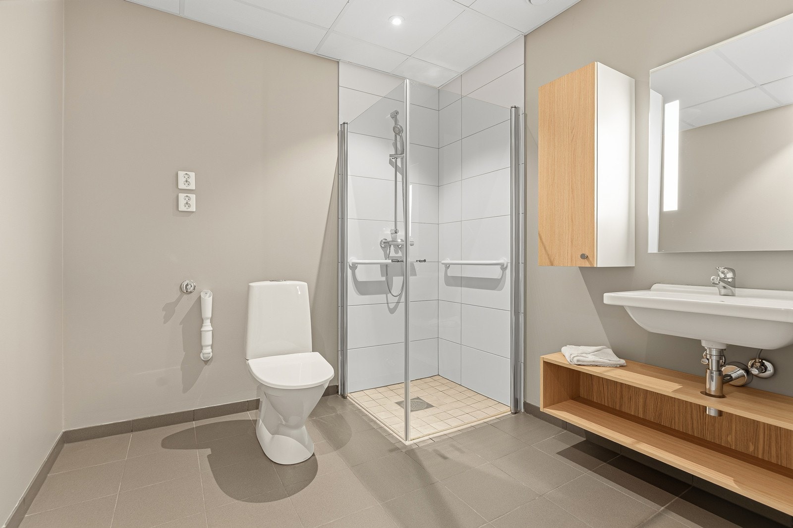 Badet er fra opprinnelig byggeår og inneholder dusjhjørne med glassdører, servantinnredning og toalett Galleribilde