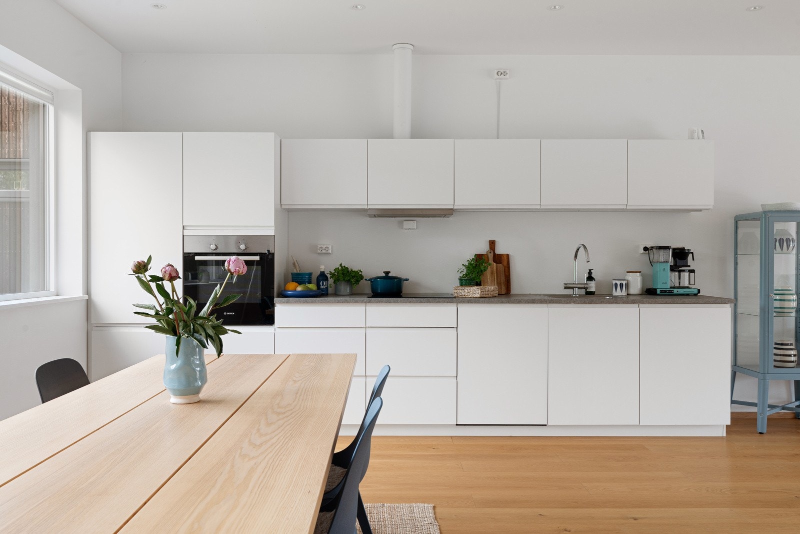 Kjøkkenet har et rent og moderne uttrykk, med slette fronter og en rolig fargepalett som tåler både hverdagsbruk og gjester.