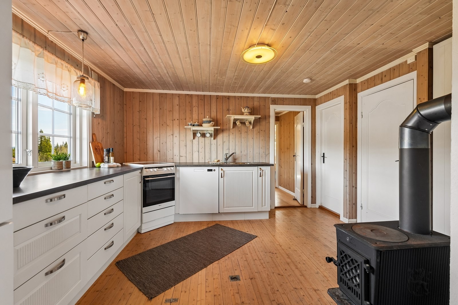 Det er plass til frittstående hvitevarer som komfyr, oppvaskmaskin og kombiskap for kjøl og frys. En vedovn bidrar til både oppvarming og ekstra hygge på kjølige dager. Galleribilde
