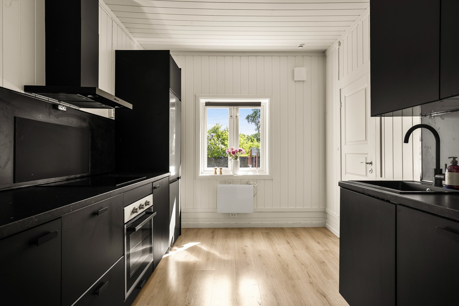 Kjøkkenet fra 2019 har moderne innredning med mørke, glatte fronter og laminat benkeplate i marmormønster. Galleribilde