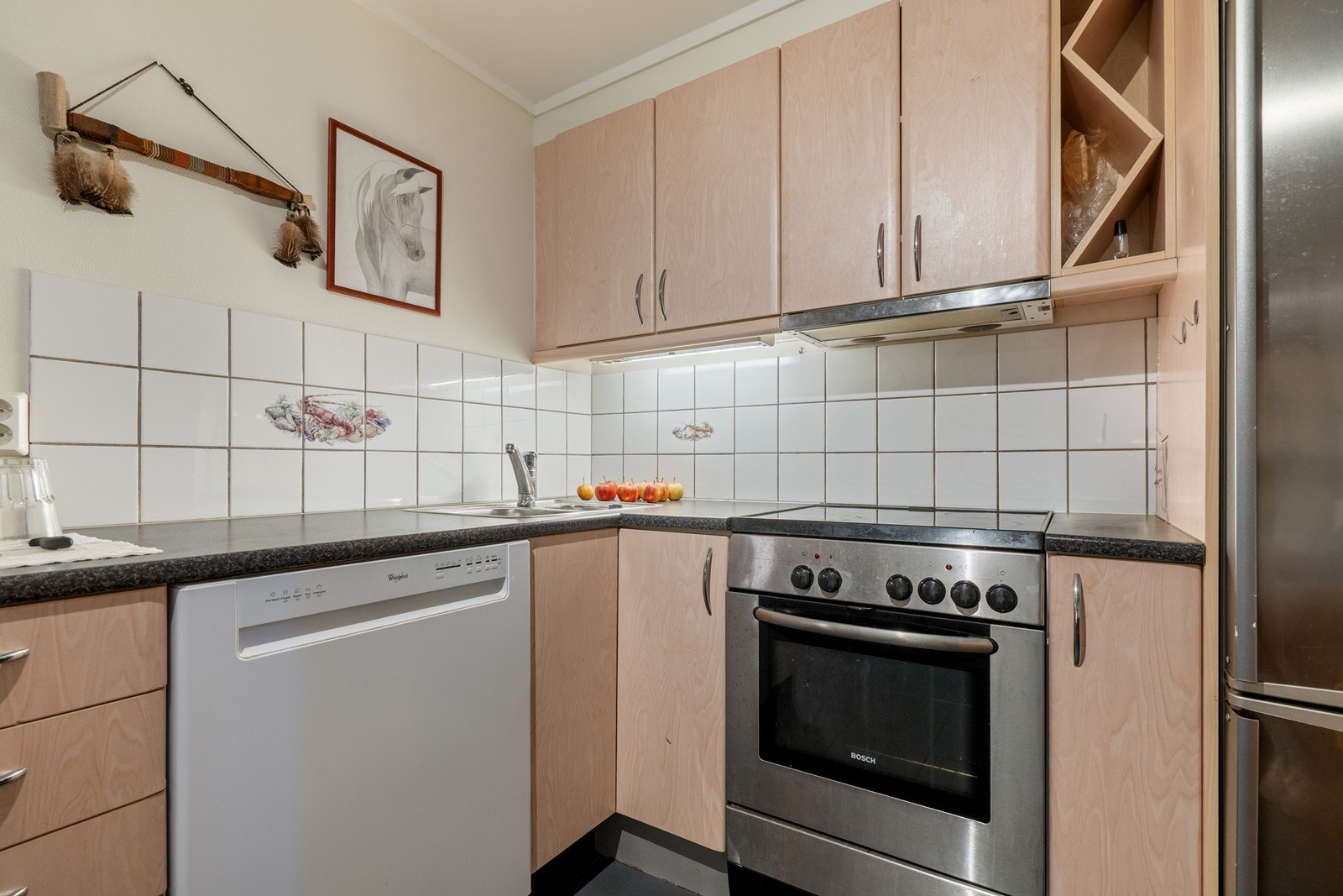 Praktisk kjøkken med glatte fronter og laminatbenkeplate som gir et tidløst og funksjonelt uttrykk. Kjøkkenet er utstyrt med frittstående hvitevarer bestående av oppvaskmaskin, komfyr og kjøl-/fryseskap (disse medfølger i handelen). Galleribilde