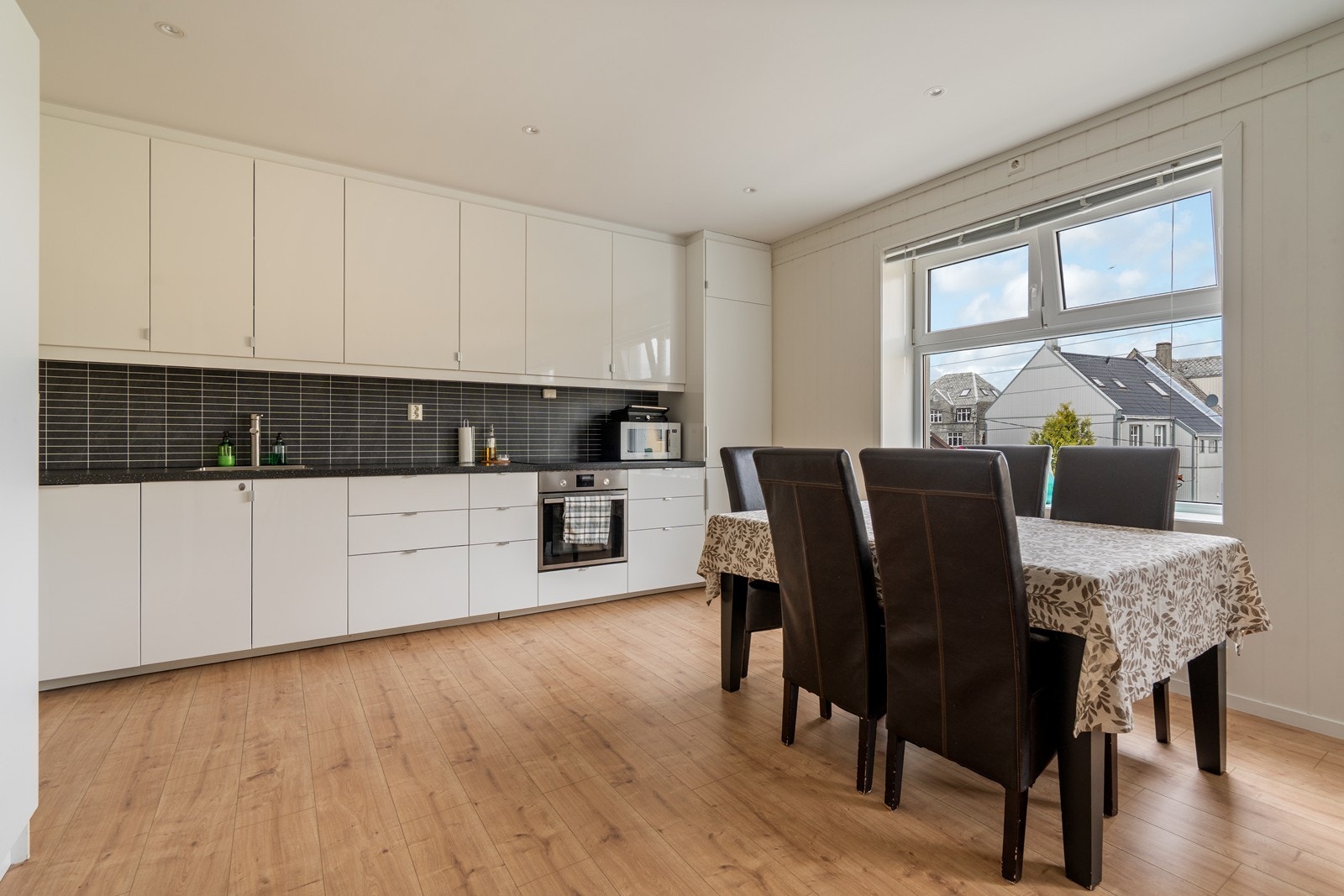 Lyst og pent kjøkken i åpen løsning mot stuen. Kjøkkeninnredningen har hvite, glatte fronter og laminatbenkeplate som gir et tidløst uttrykk. Galleribilde