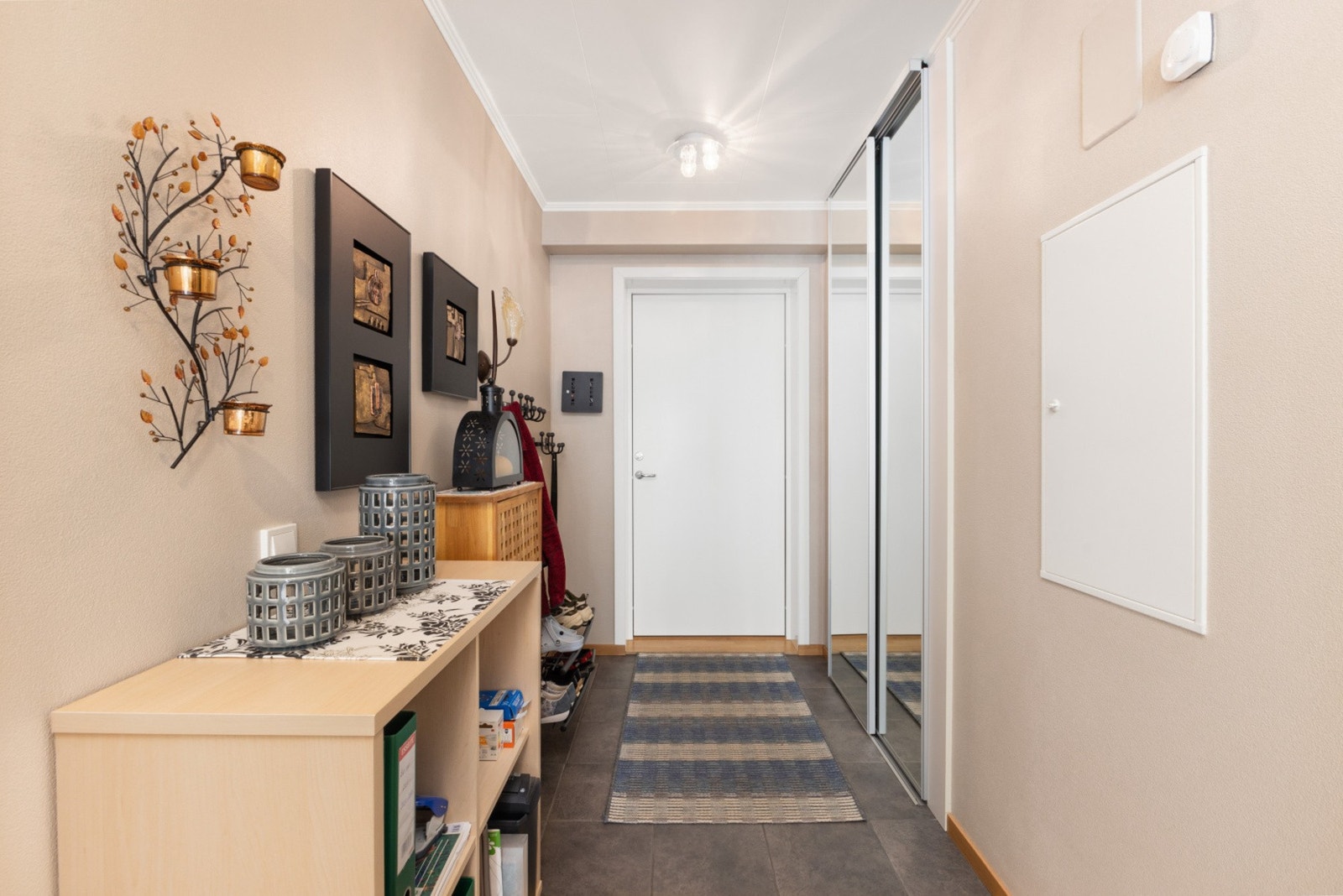 Innbydende entré med god plass til yttertøy og sko. Fra gangen er det enkel adkomst til leilighetens øvrige rom, og de lyse overflatene bidrar til et trivelig førsteinntrykk. Praktiske oppbevaringsmuligheter gjør hverdagen både ryddig og oversiktlig Galleribilde