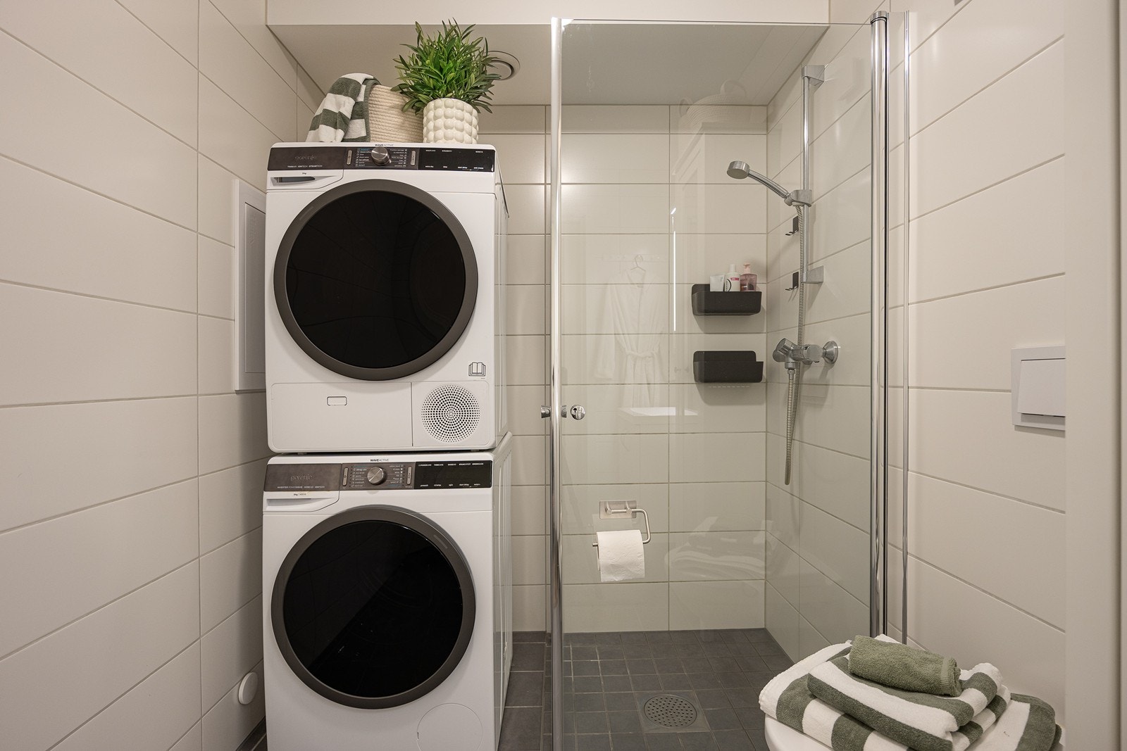 Badet er utstyrt med vegghengt toalett, dusjhjørne og opplegg for vaskemaskin og tørketrommel. Galleribilde