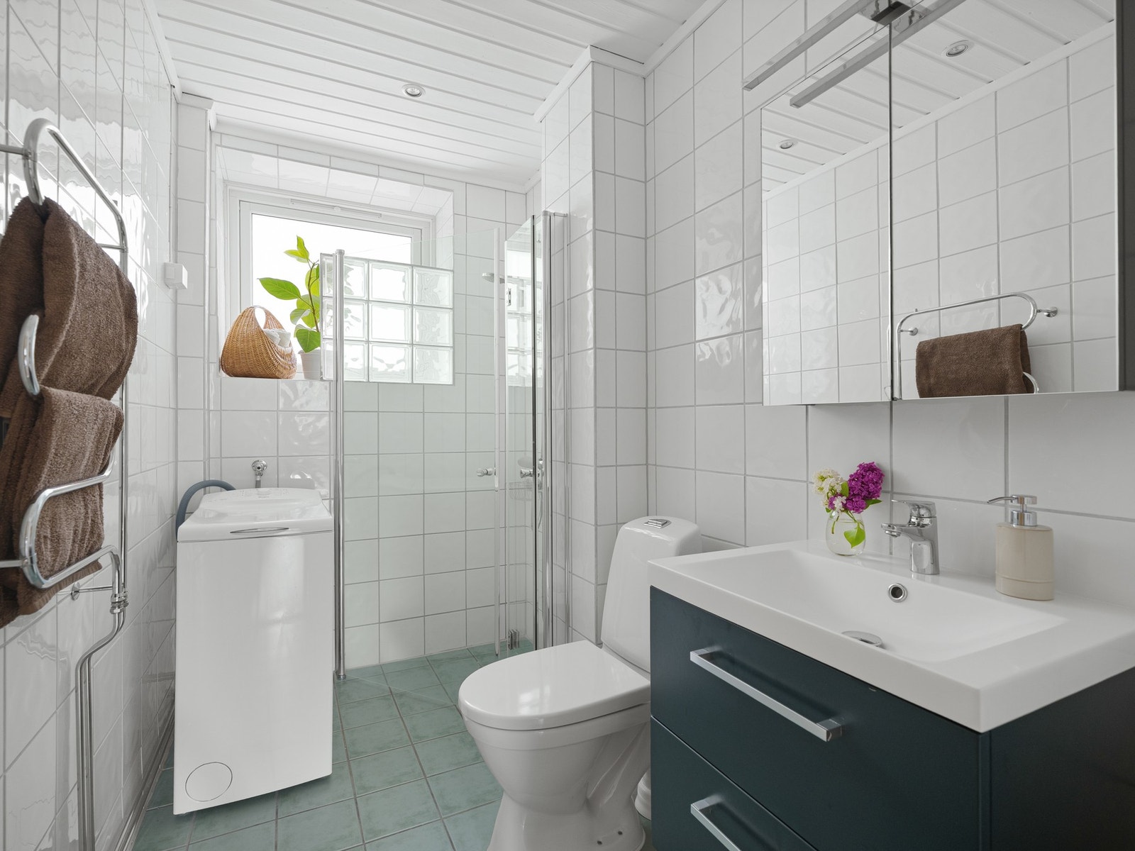 Badet er innredet med dusjhjørne, servant med skuffer, speilskap og toalett. Det er både plass og opplegg til vaskemaskin her inne. Galleribilde