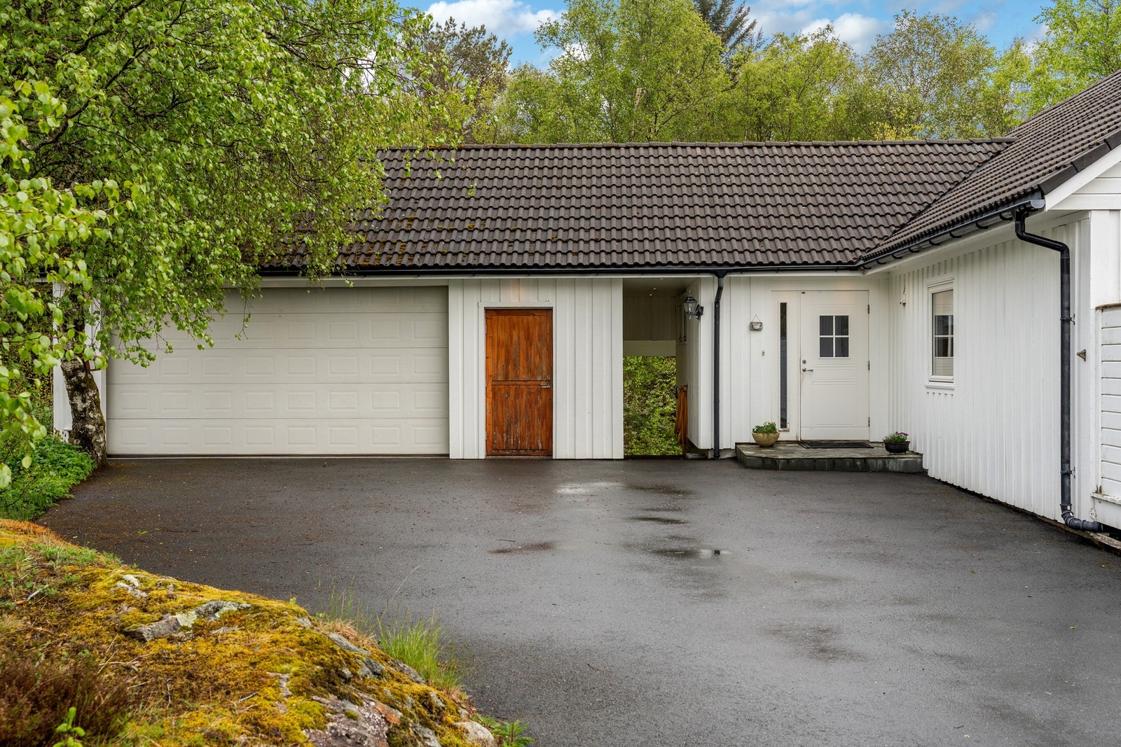 Asfaltert gardstun, med stor dobbel garasje. Galleribilde