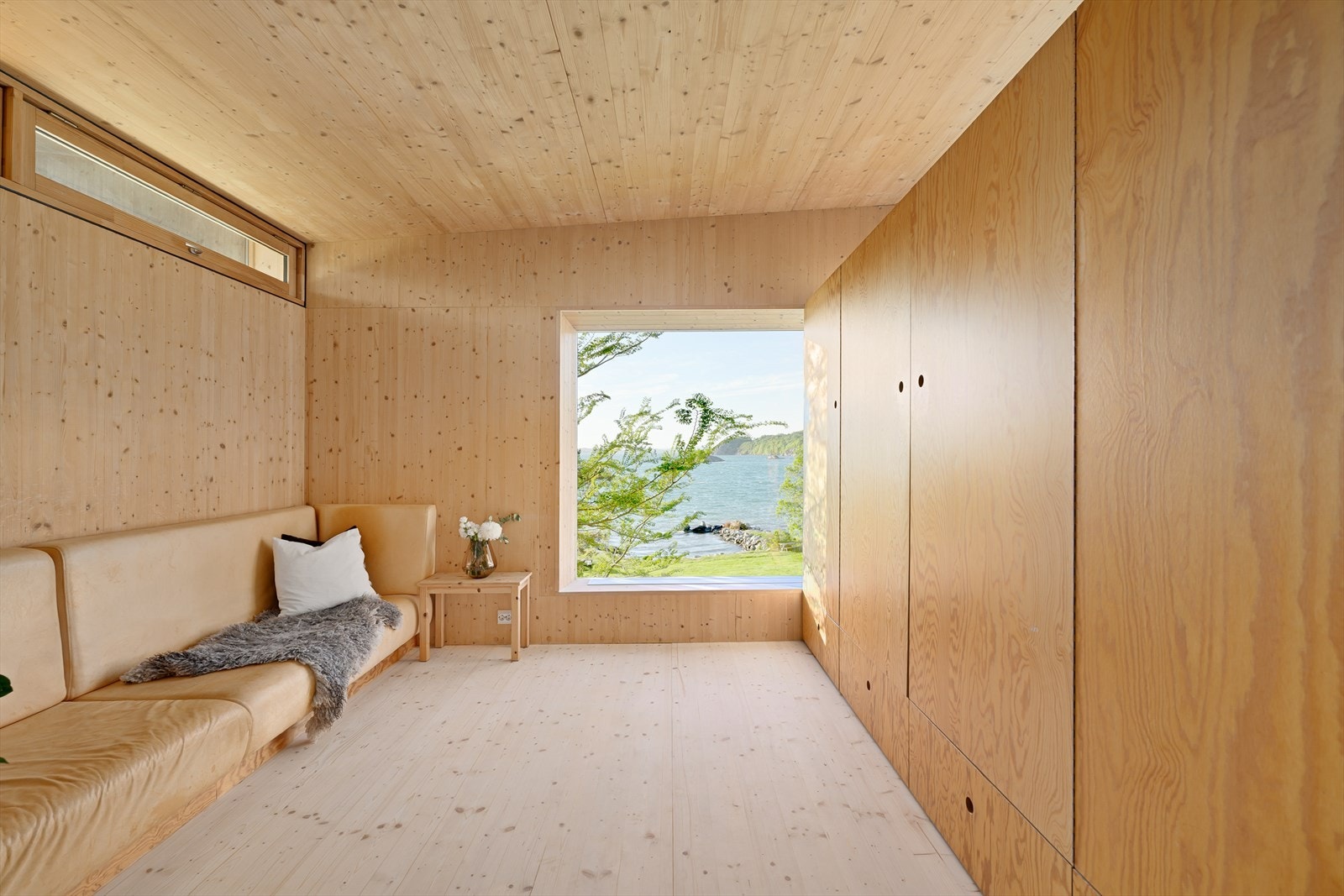 Skyvedør inn til skjermet tv-stue med stedbygd sofa i husets nordvestre hjørne, og også her er utsikten fortreffelig Galleribilde