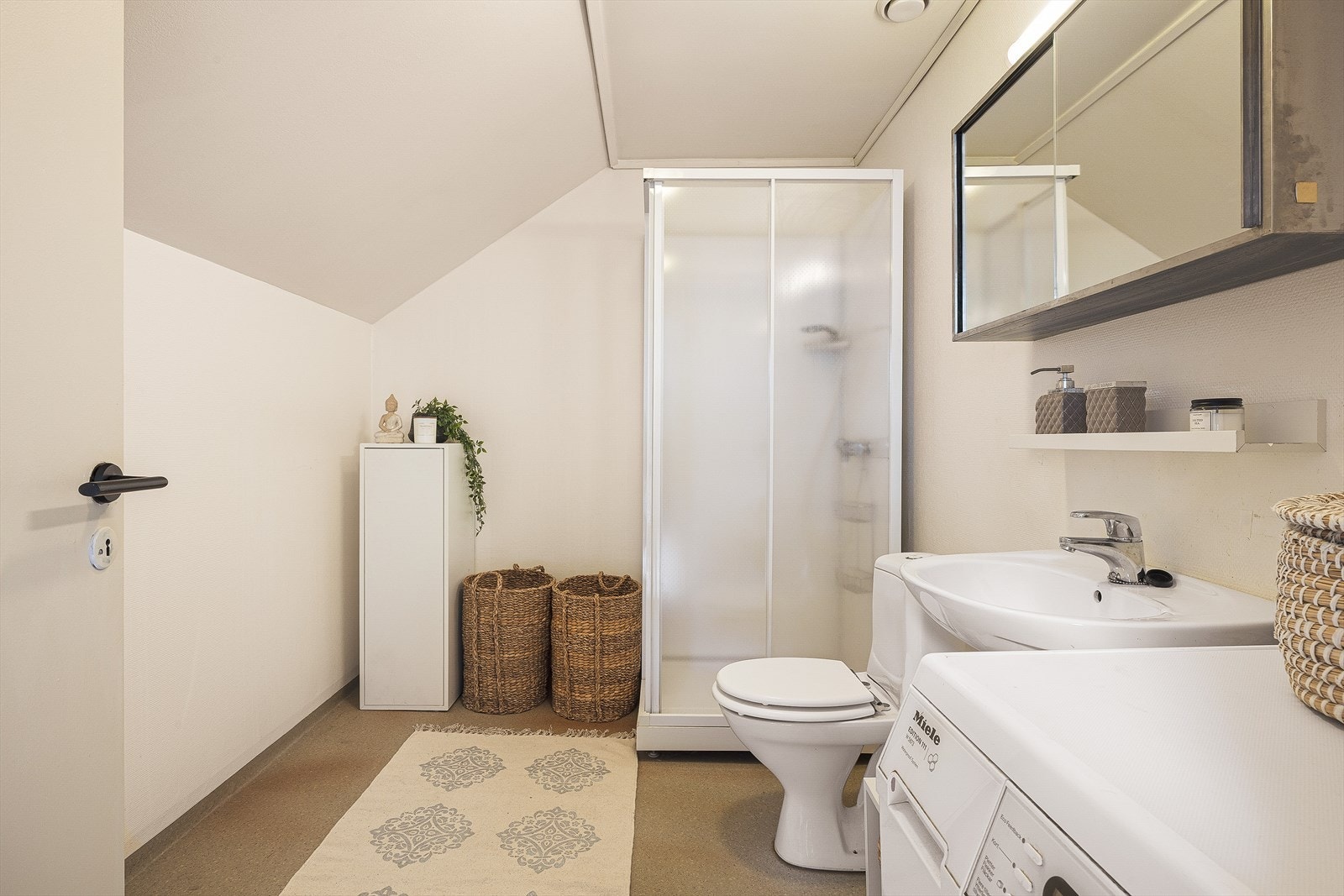 Her har man plass til alt en trenger i hverdagen. Badet har fasiliteter som dusjkabinett, opplegg til vaskemaskin, servant og rom for ekstra lagringsplass. Galleribilde